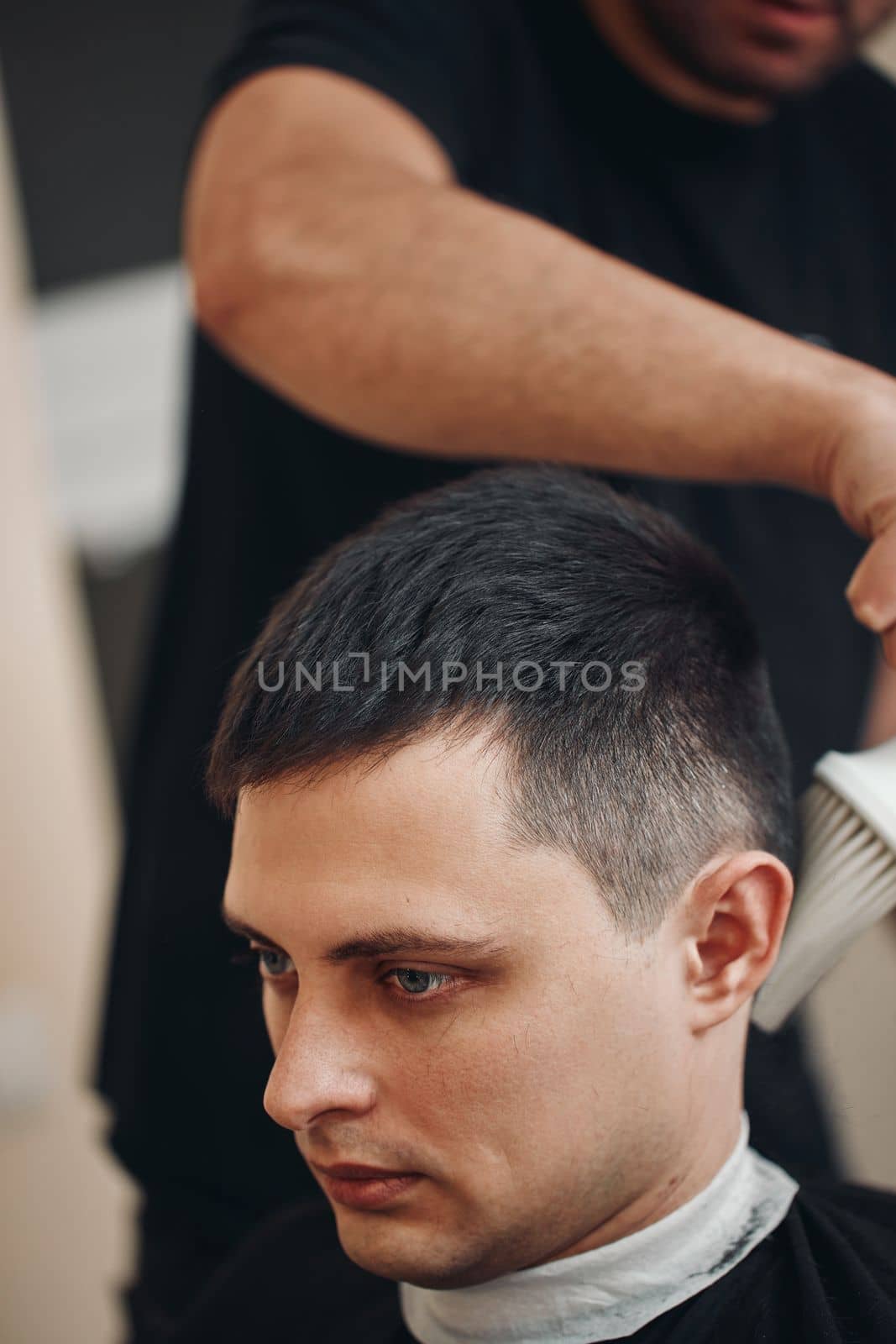 hairdresser does haircut for caucasian man in barber shop