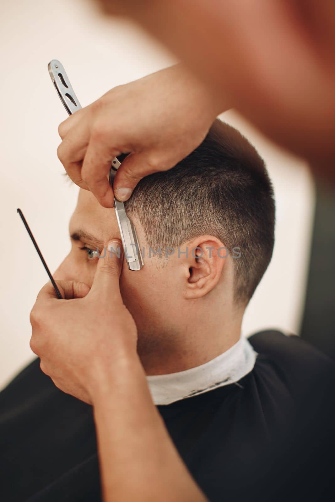 Barber shaving bearded man with razor in barber shop. close-up