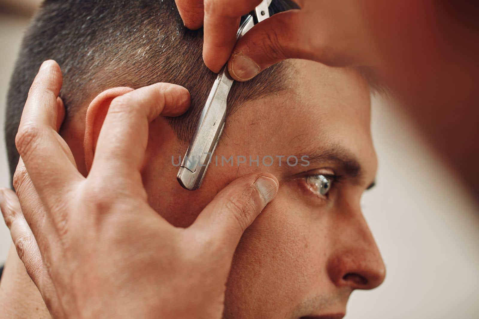 Barber shaving bearded man with razor in barber shop. close-up