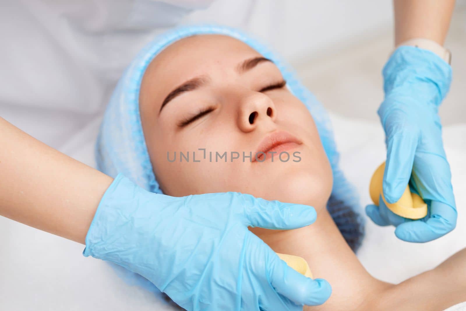 beautician cleanses skin of beautiful woman with sponge. close-up. Perfect cleaning, spa treatment skincare face.
