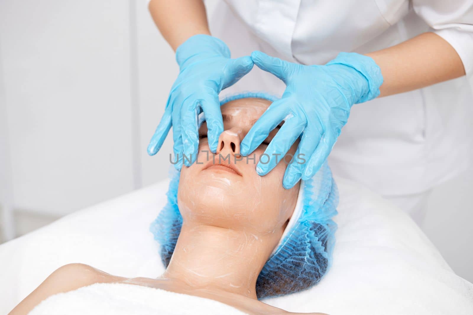 young beautiful woman receiving facial massage at spa salon