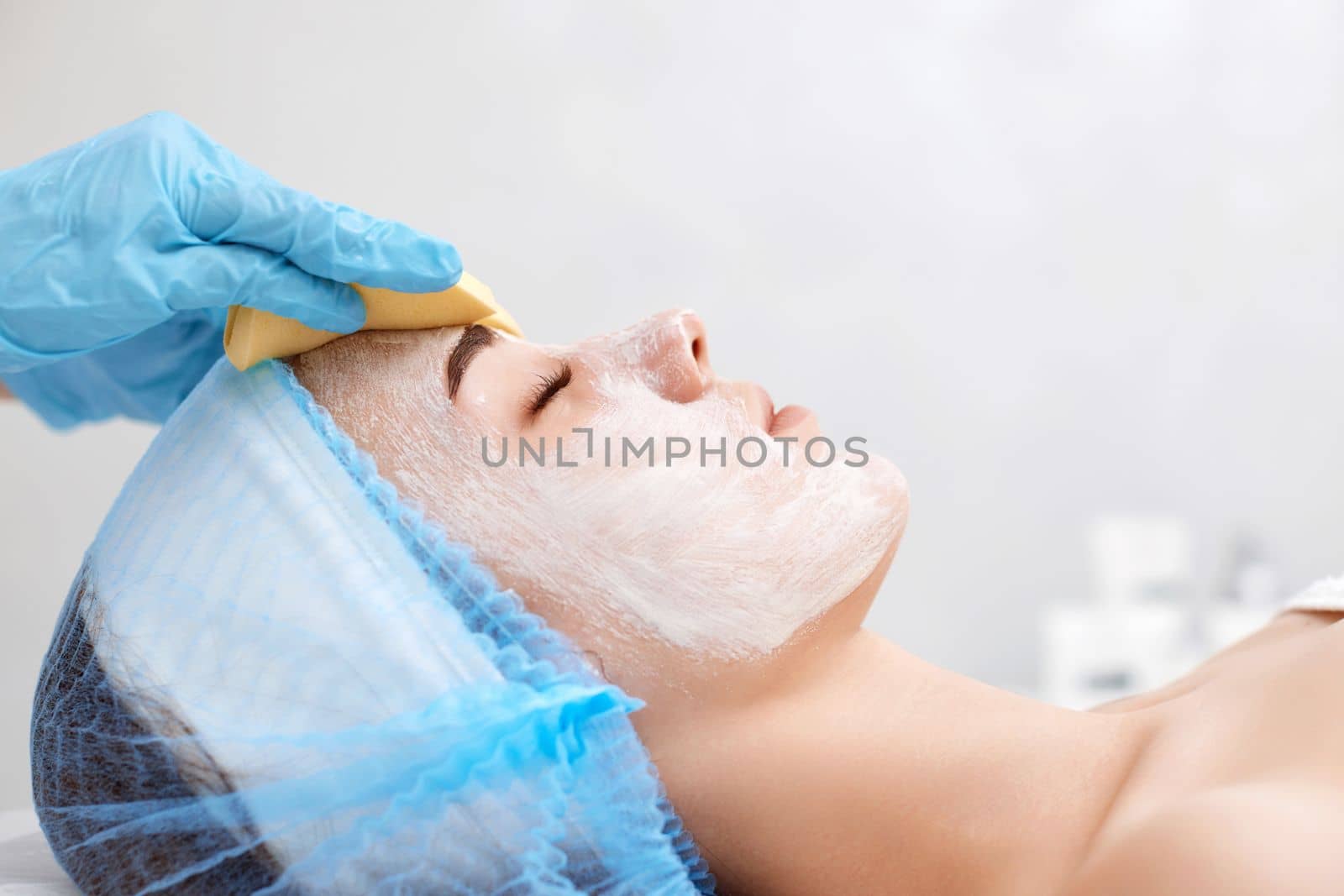 beautician cleanses skin of beautiful woman with sponge. Perfect cleaning, spa treatment skincare face.