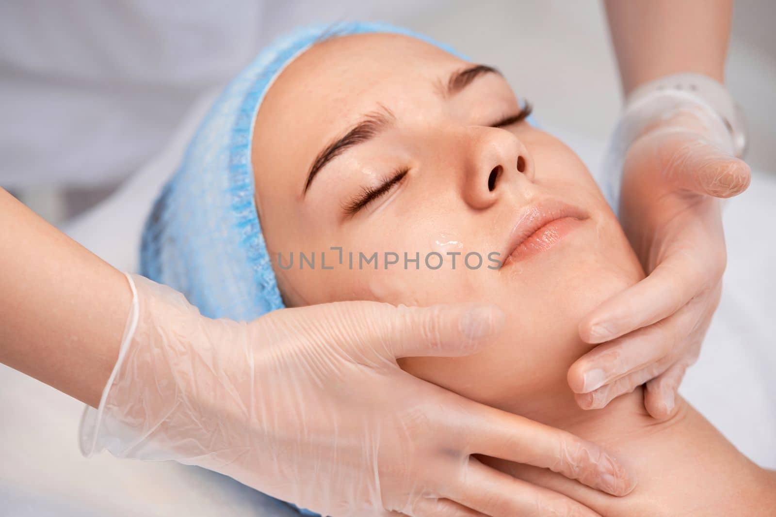 young beautiful woman receiving anti-stress facial massage at spa salon