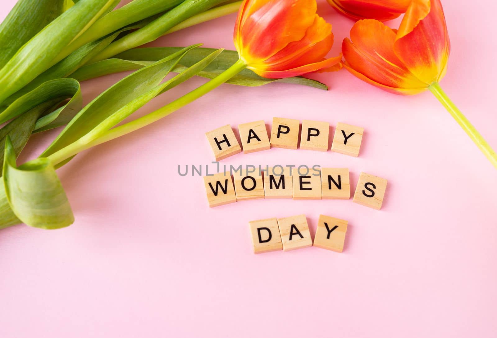 March 8, postcard. Happy Women's Day text sign with orange tulips on pink background. Stylish flat lay with flowers and text, greeting card