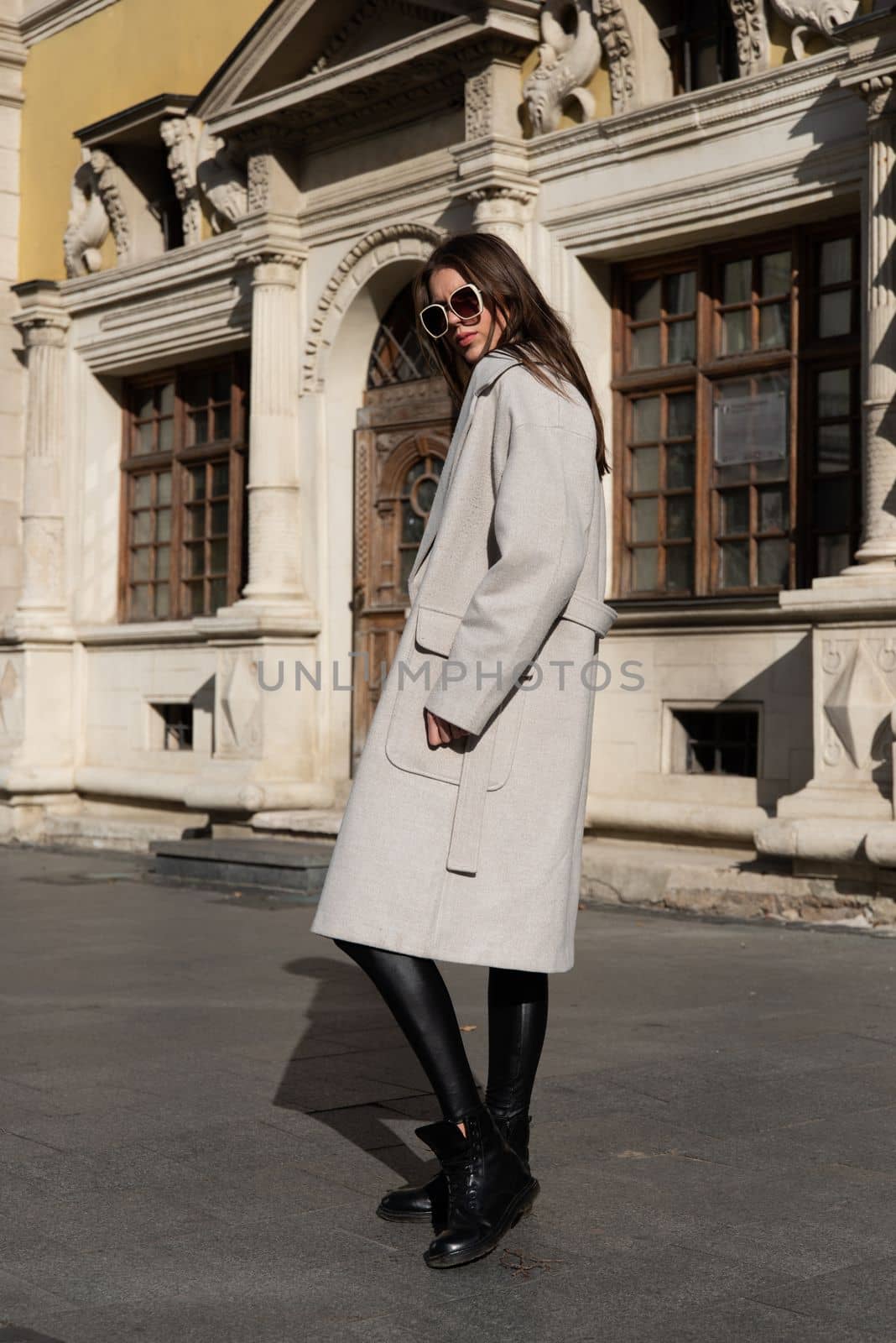 Street style, autumn, spring fashion concept: fashionable woman wearing luxury beige coat, sunglasses, wide leg black leggings, ankle bots, walking in street by Ashtray25