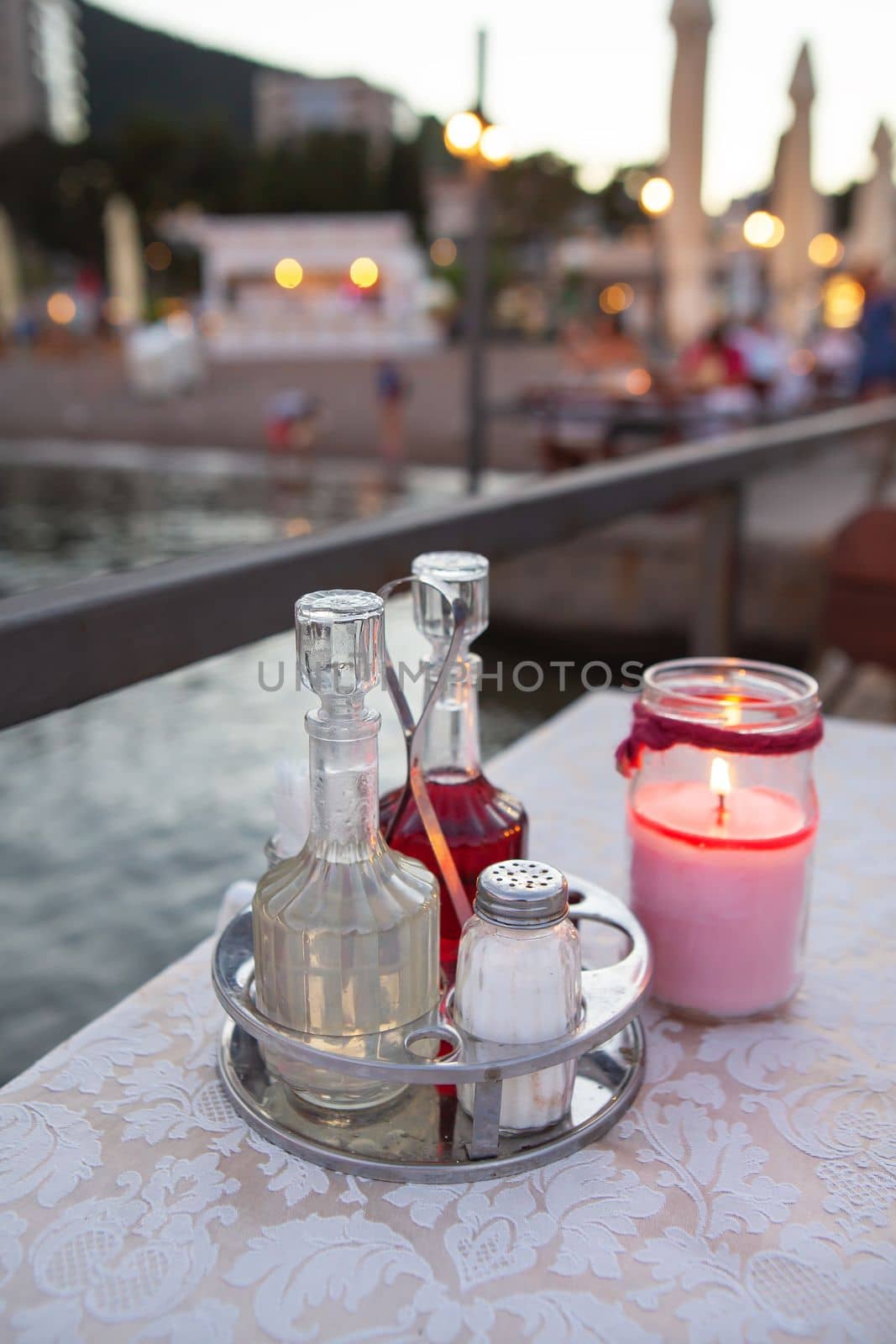 The terrace of the restaurant by the sea, there is a candle on the table. Against the backdrop of a beautiful resort town. Romantic dinner by the sea. by sfinks