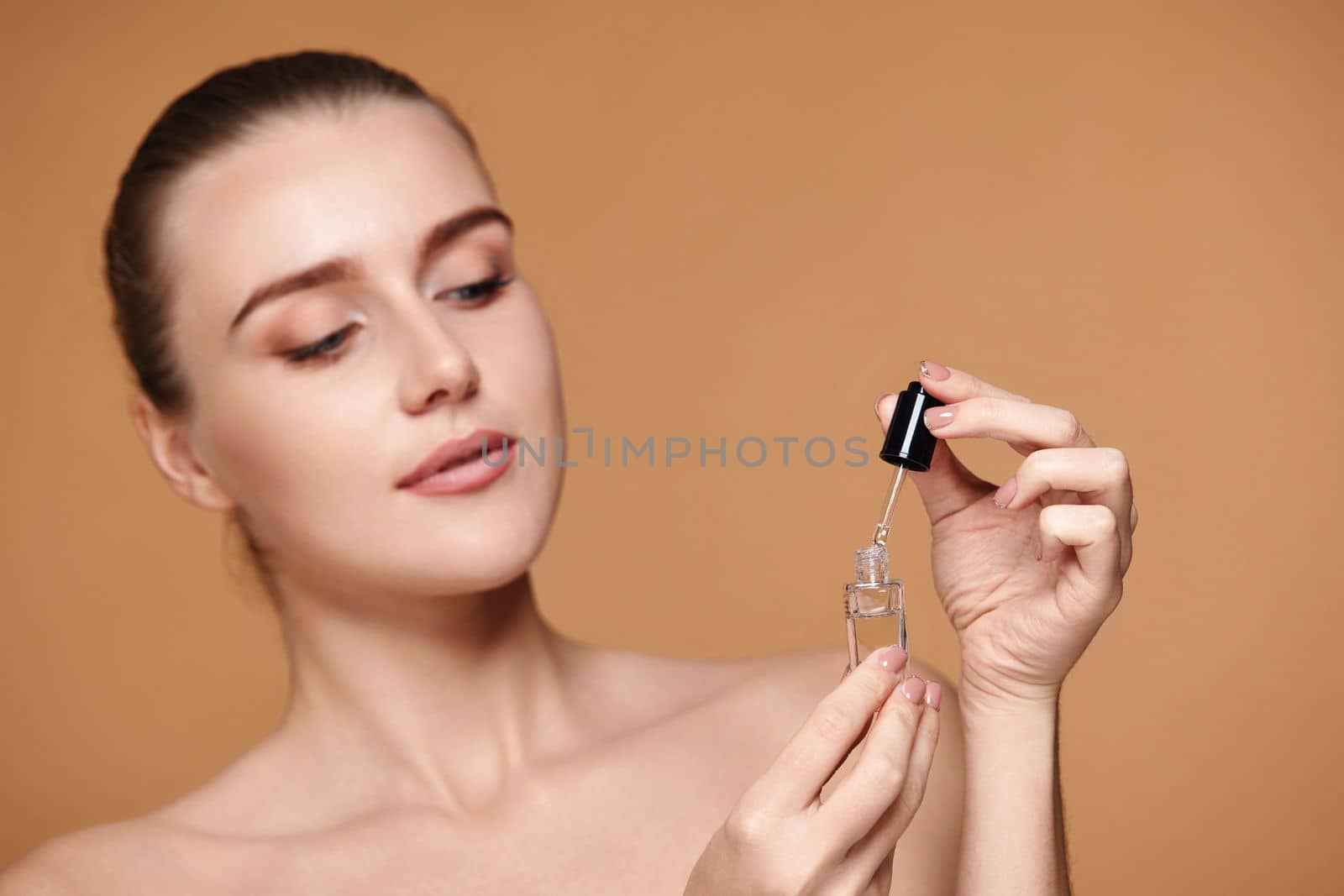 beautiful woman holding bottle with serum for skin care on beige background