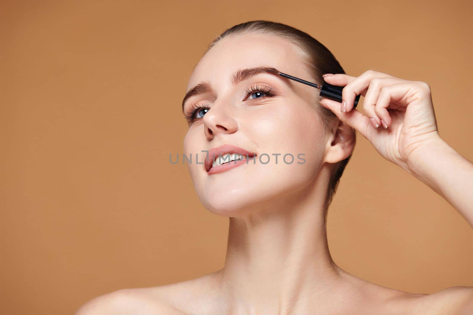 Beautiful woman with perfect shape eyebrows on beige background. Natural make up. copy space