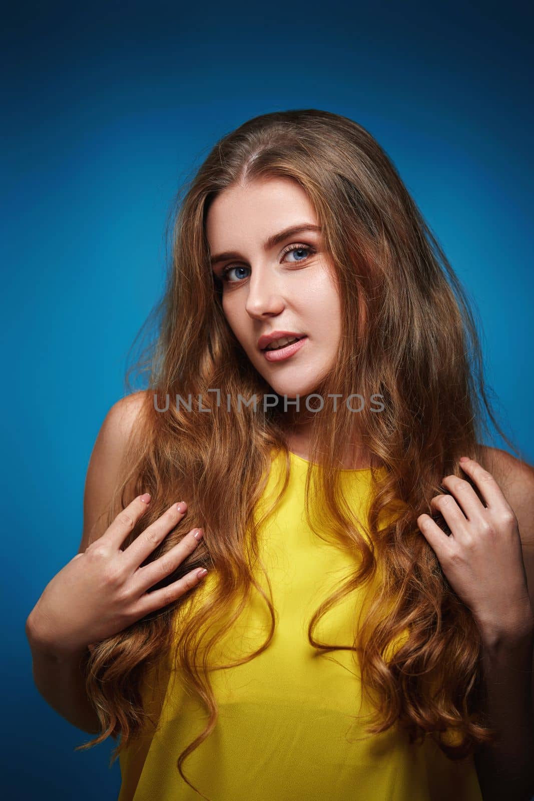 happy woman with strong healthy curly hair dancing on blue background