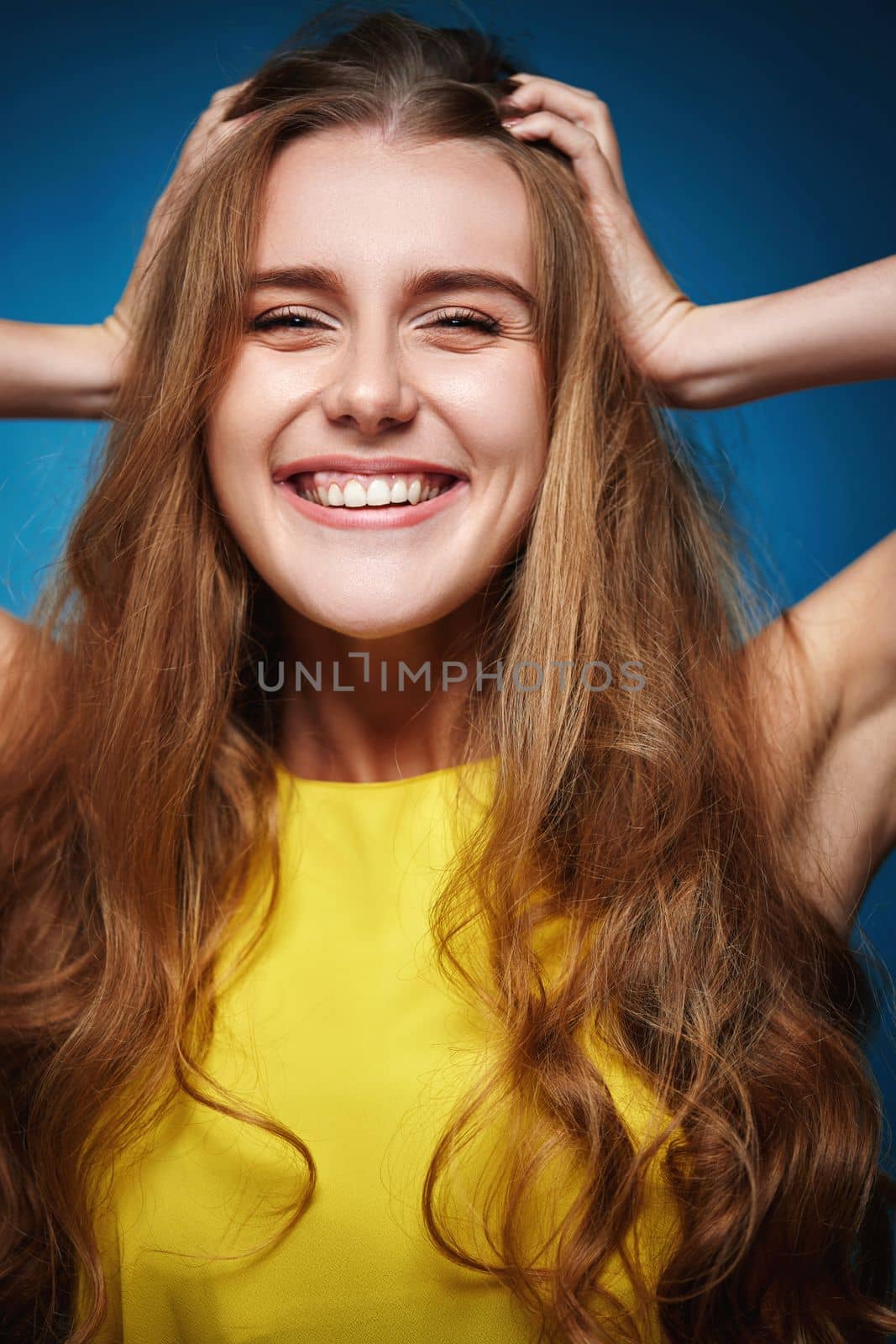 funny woman with strong healthy curly hair dancing on blue background