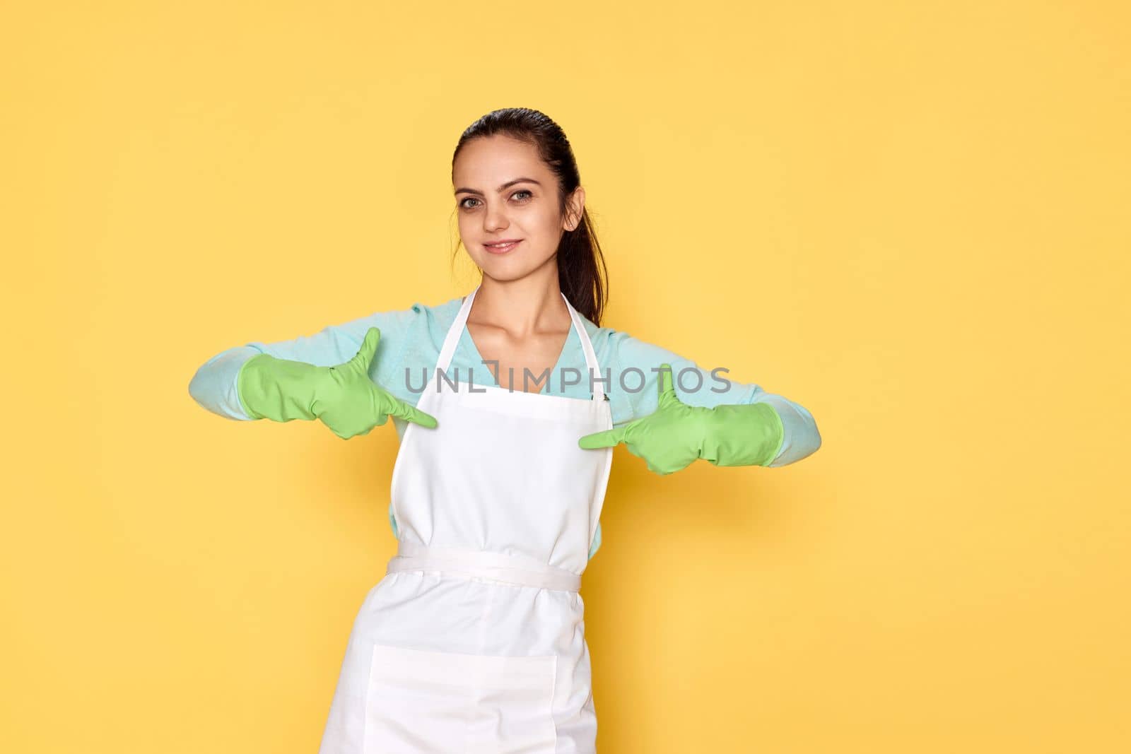 smiling caucasian woman in gloves pointing oneself with fingers on yellow background. cleaning