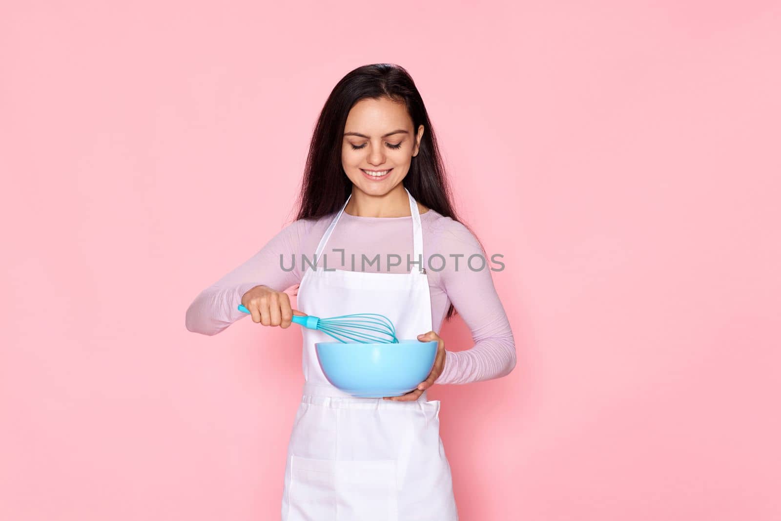 happy housewife woman holding whisk and bowl on pink background