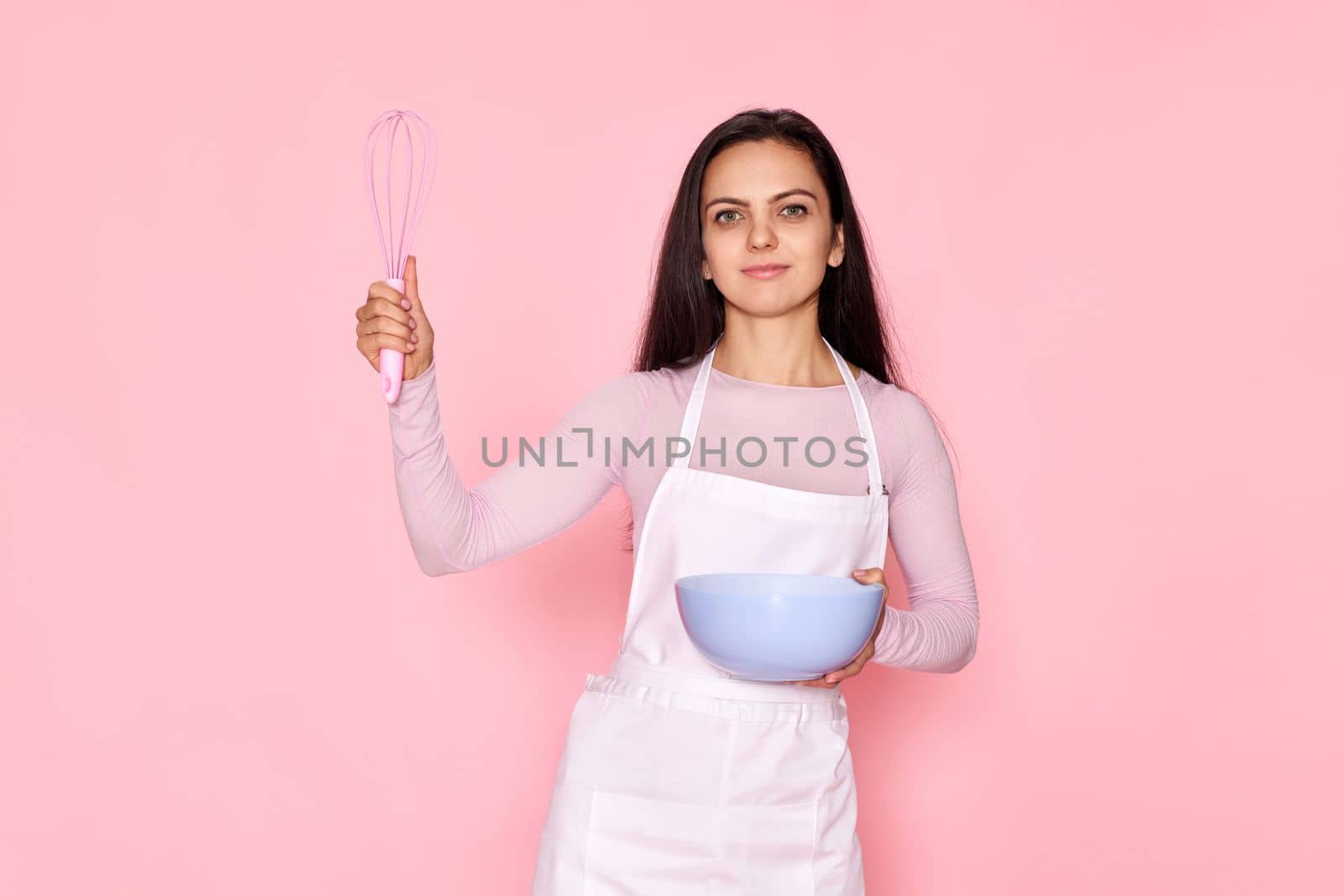 beautiful cooker woman using bowl and whisk on pastel pink background