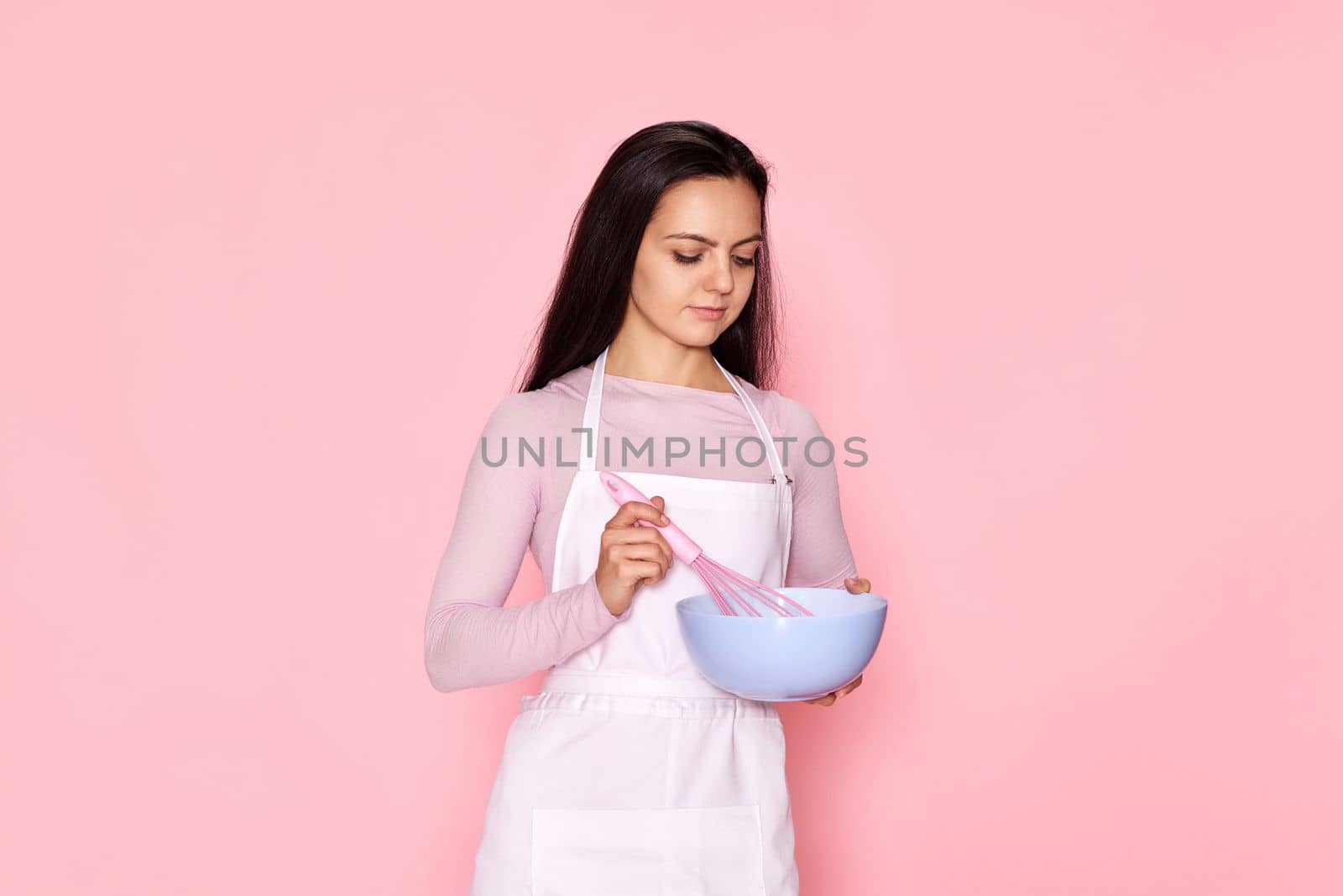 beautiful chef woman using bowl and whisk on pink background