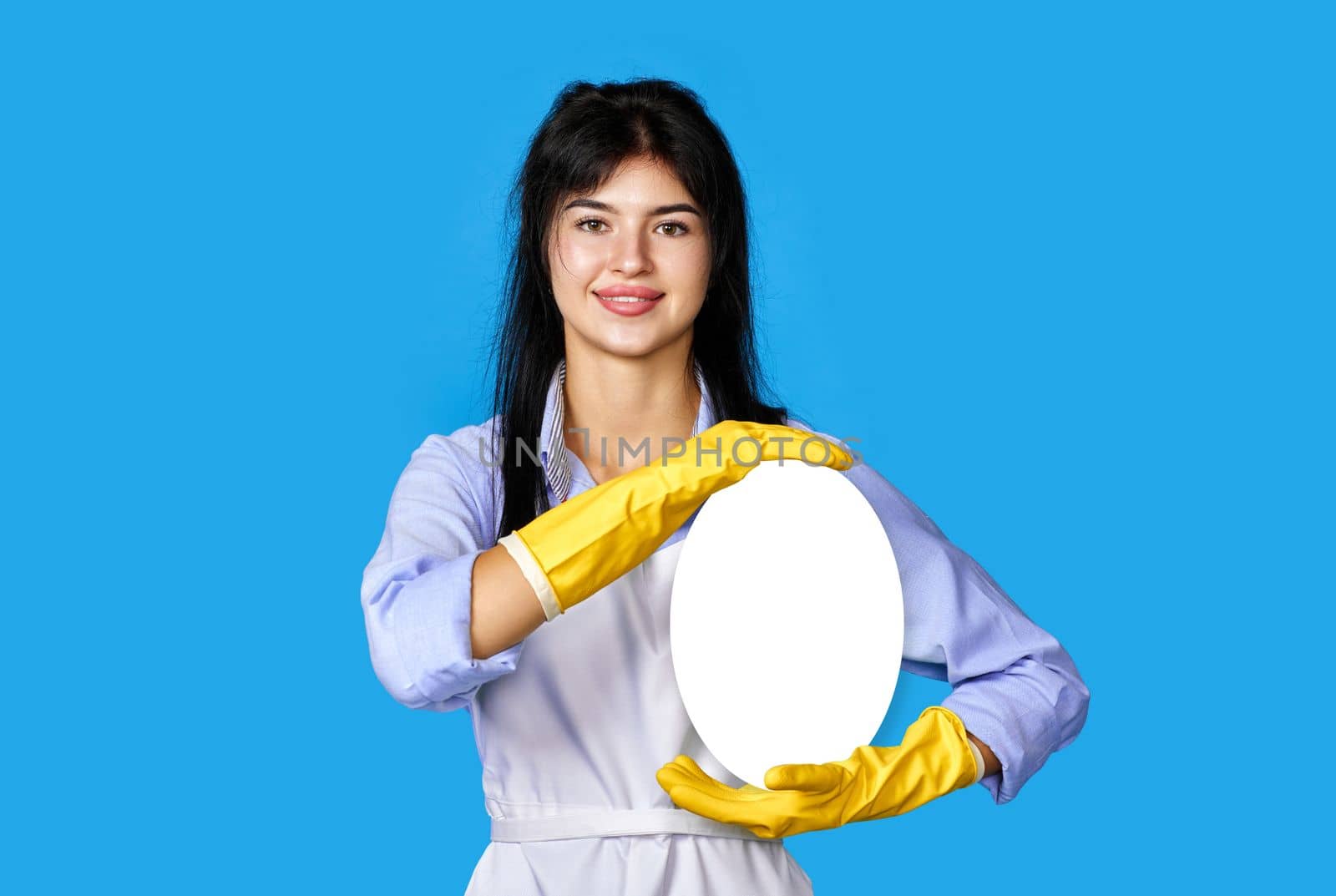 smiling woman in yellow rubber gloves and cleaner apron showing copy space on blue background. cleaning