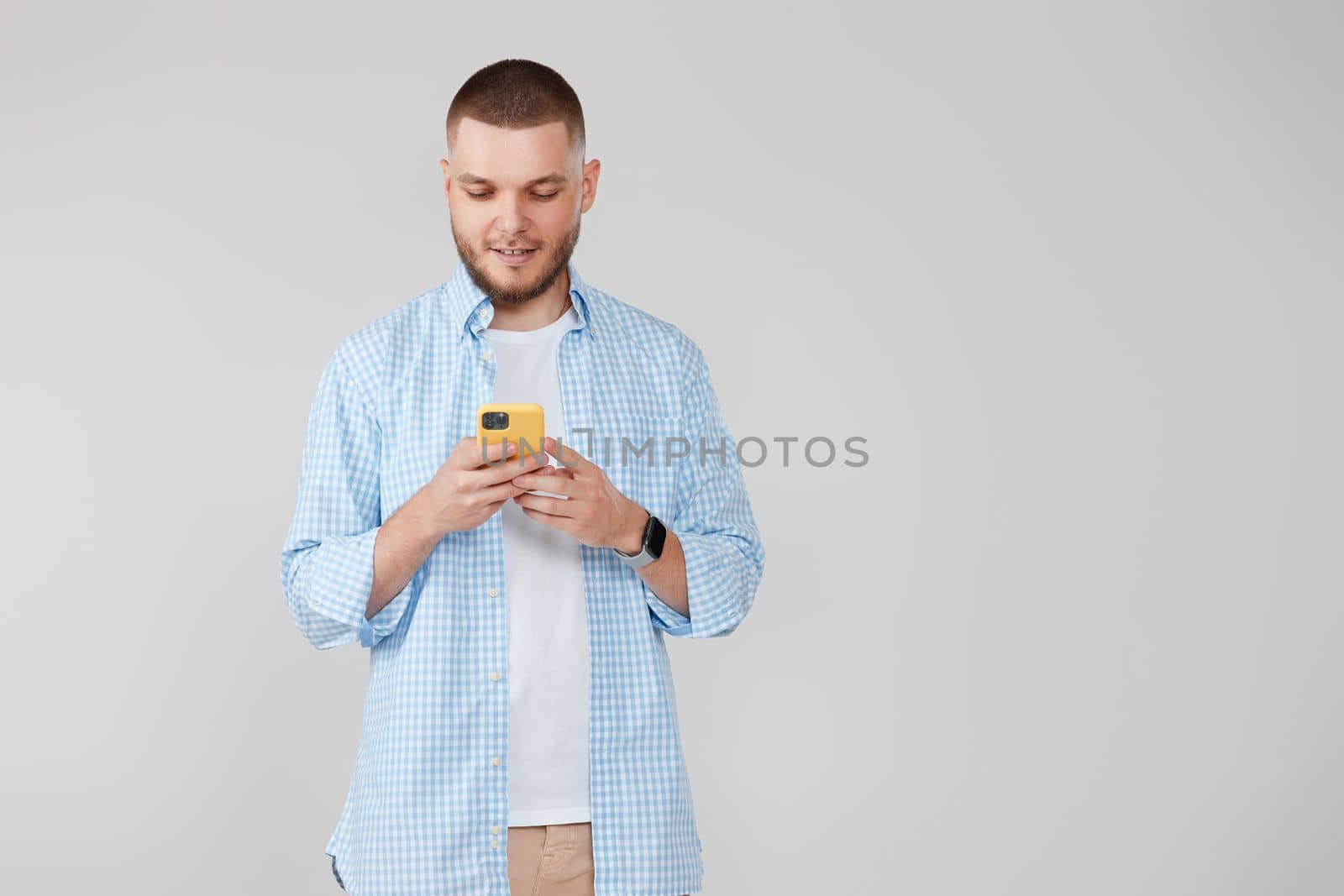 smiling man looking at mobile cell phone surfing internet. copy space