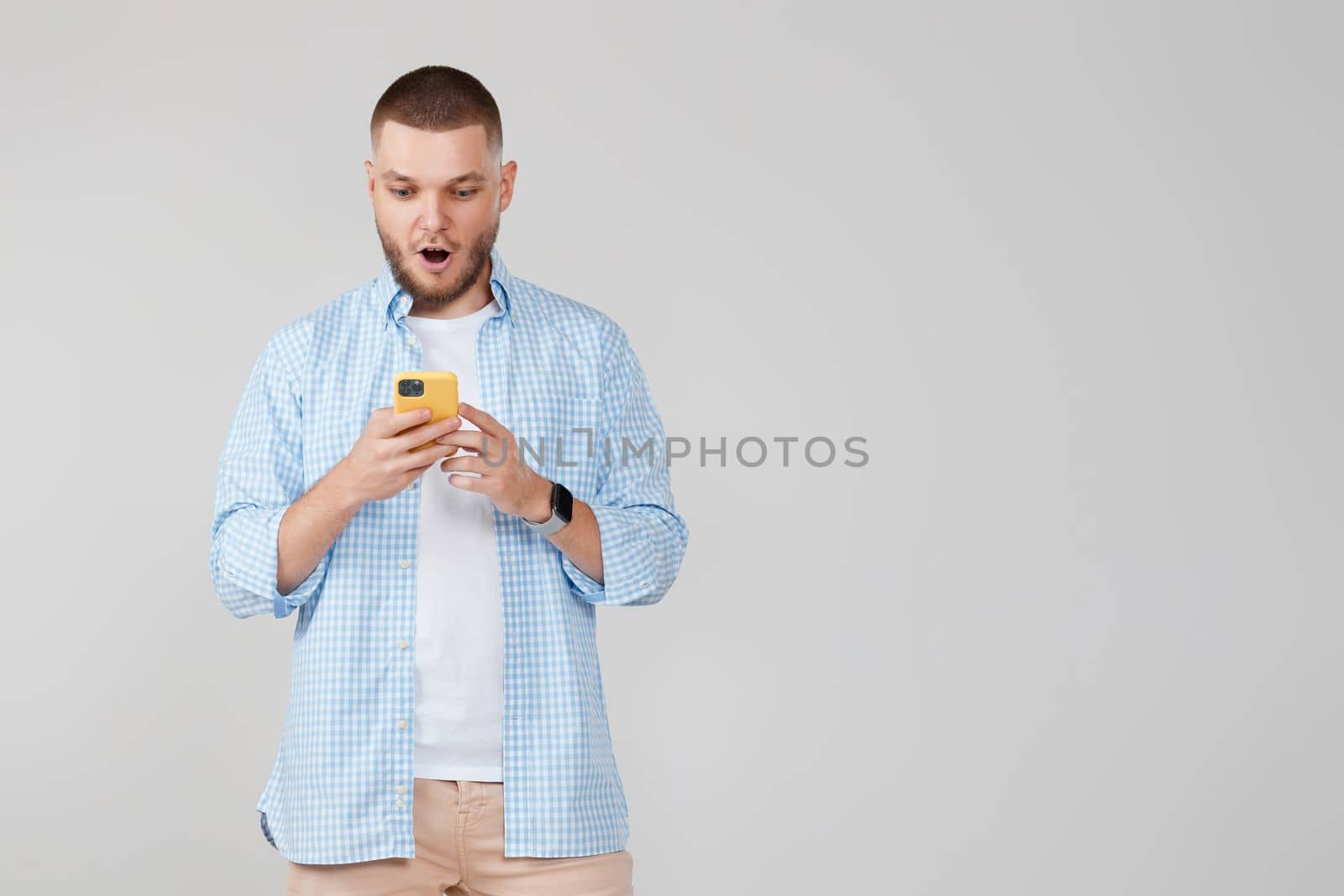 surprised handsome man with mobile cell phone surfing internet. copy space