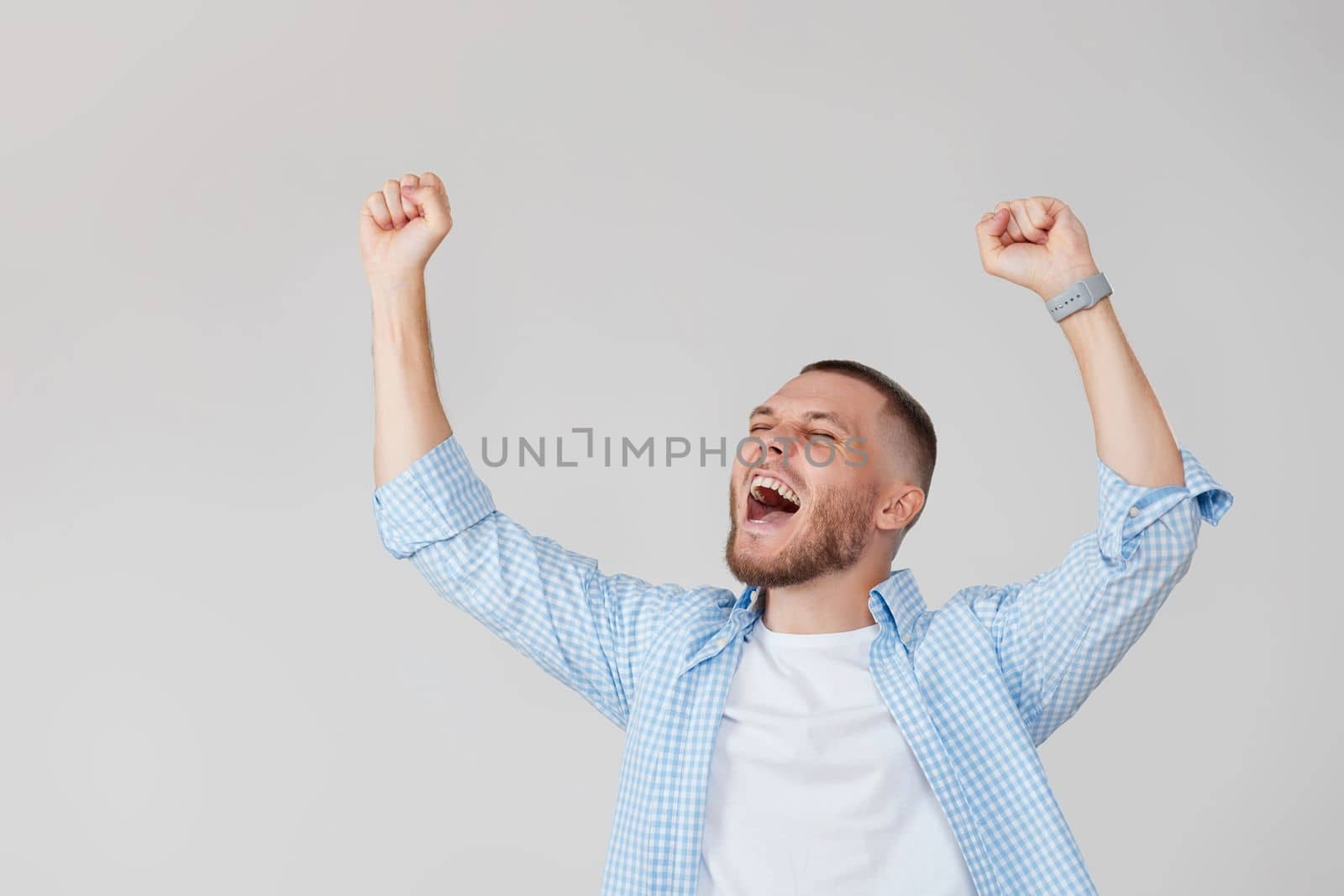 amazed young man celebrating victory on gray background.