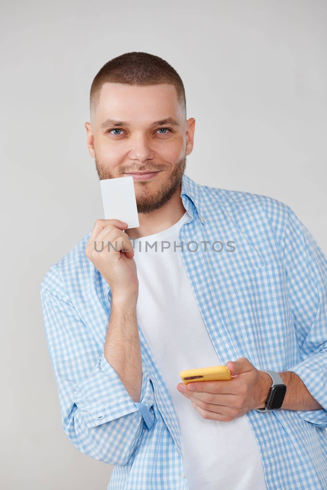 smiling handsome man with mobile cell phone and credit bank card making purchases by app. E-commerce concept