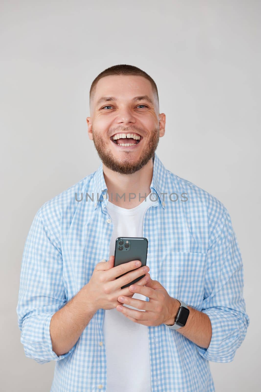 happy smiling bearded man in blue t-shirt messaging with mobile cell phone