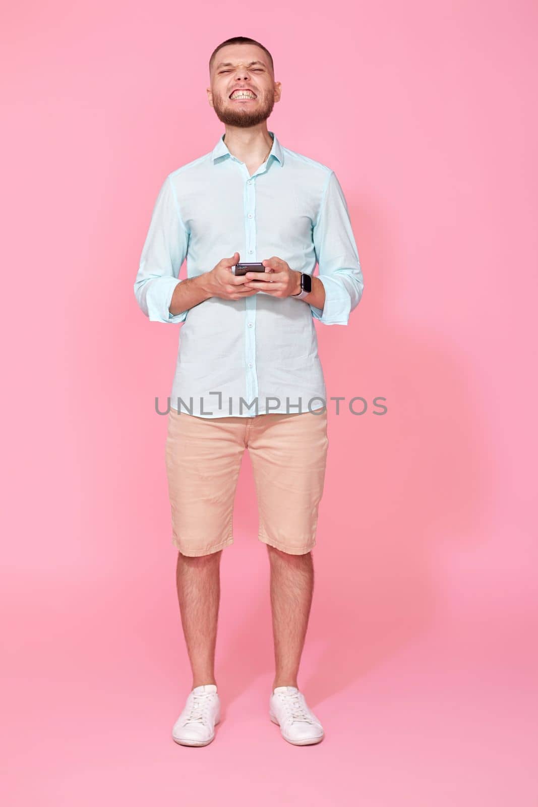 happy handsome bearded man in summer blue t-shirt messaging with mobile cell phone