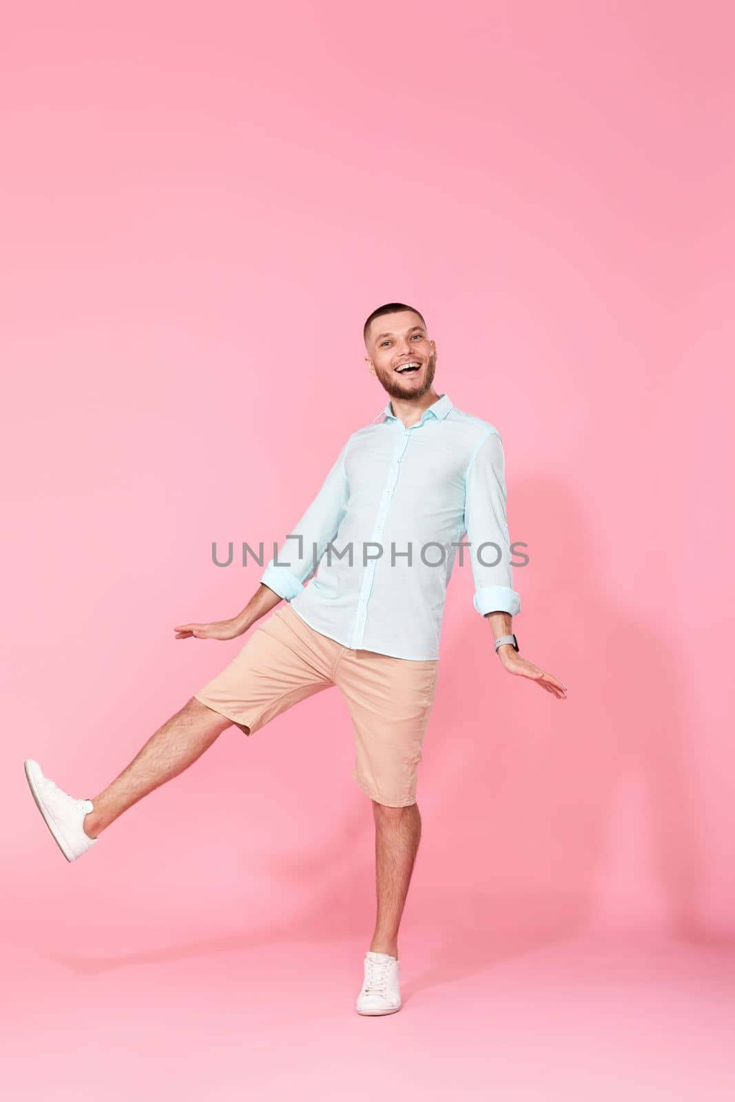 happy funny young man in casual shirt posing isolated on pink background. Having fun, fooling around