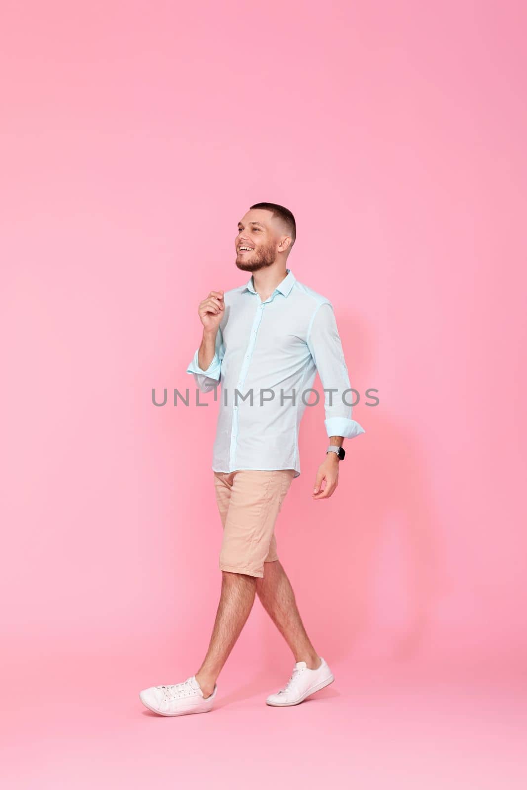 handsome happy man walks isolated on pink background. vacation summer.