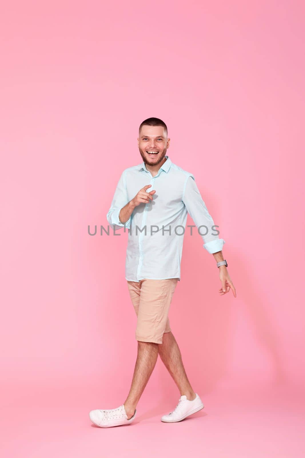 handsome happy man walks isolated on pink background. vacation summer.