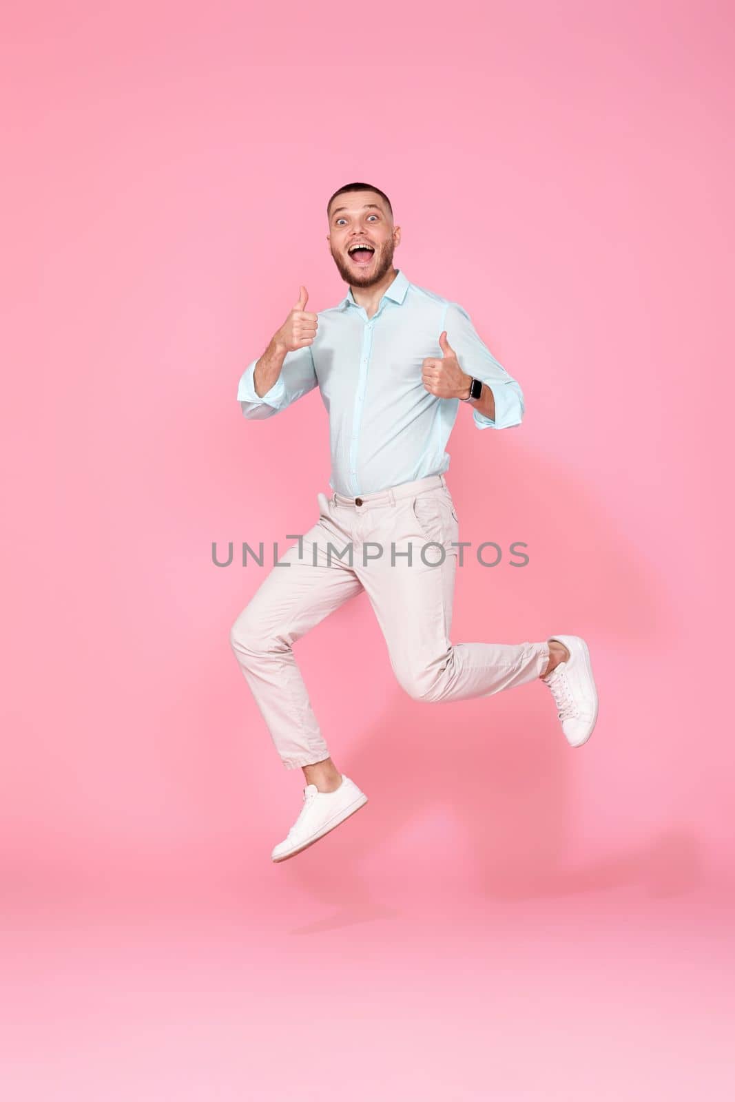 young man in summer clothes jumping isolated on pink background. Full length