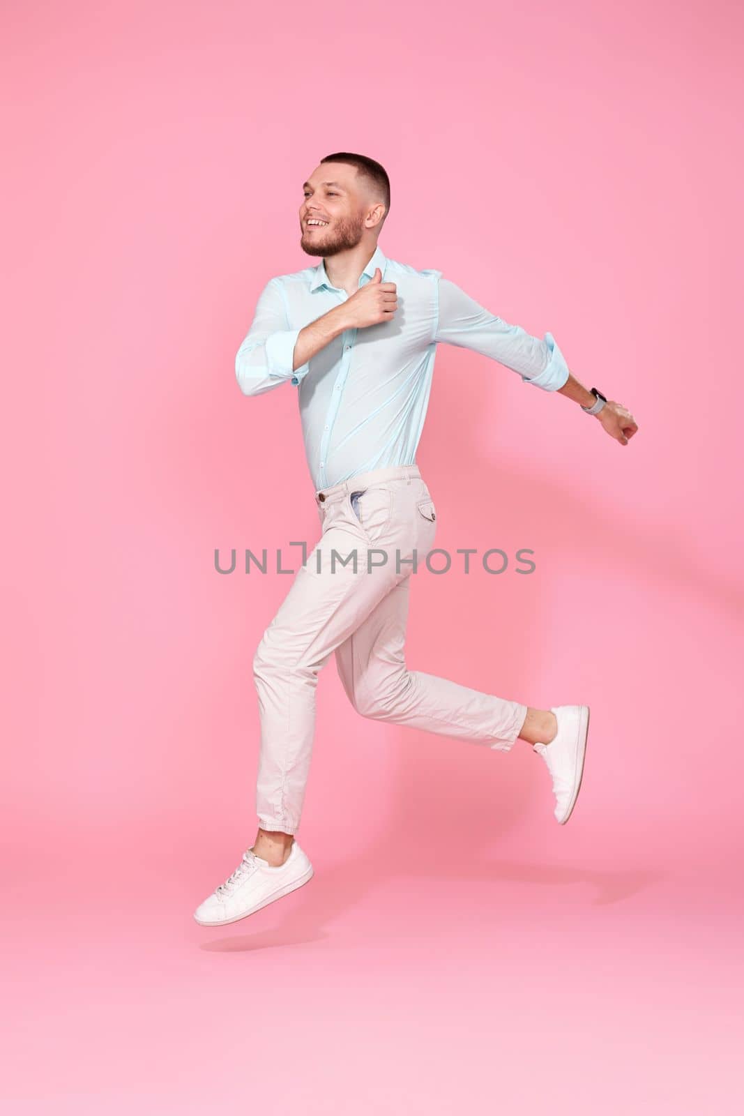 young man in summer clothes jumping isolated on pink background. Full length