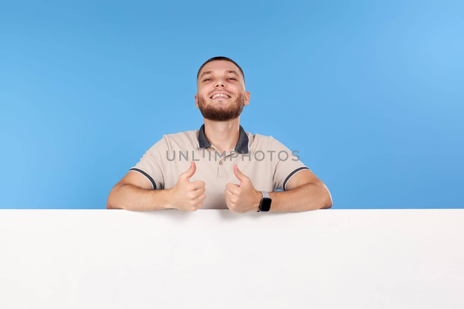 Portrait of cheerful man leaning on board with empty copy space isolated on blue background