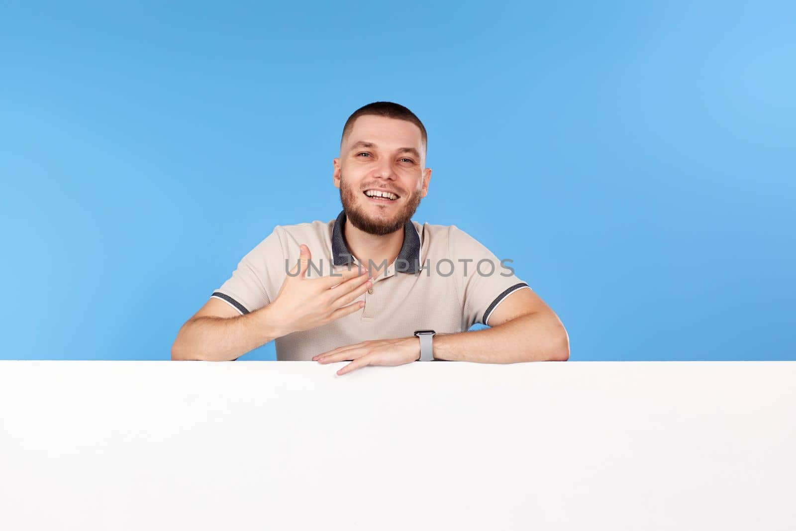 Portrait of friendly man in casual t-shirt with board with empty copy space isolated on blue background