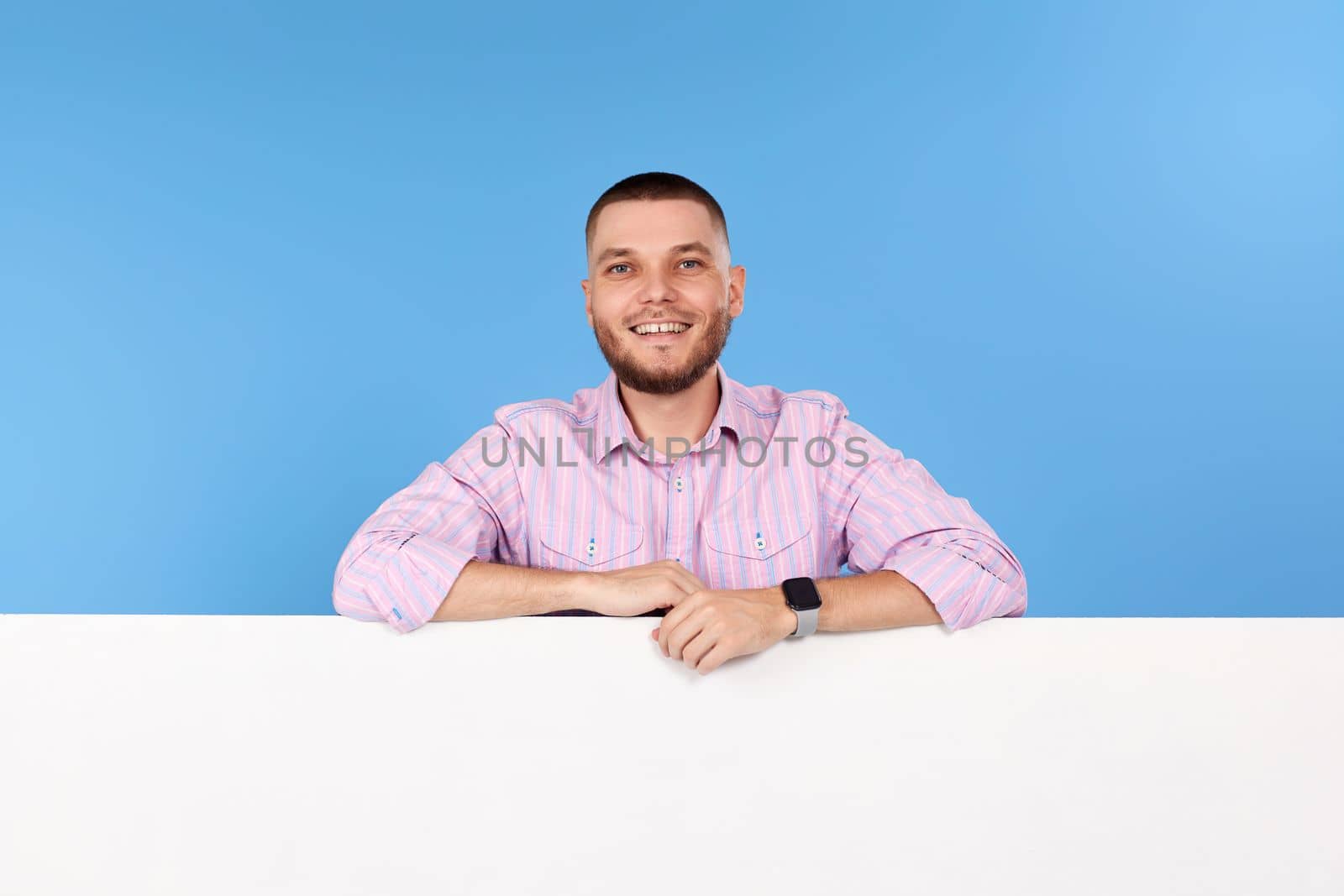 Portrait of cheerful man leaning on board with empty copy space isolated on blue background