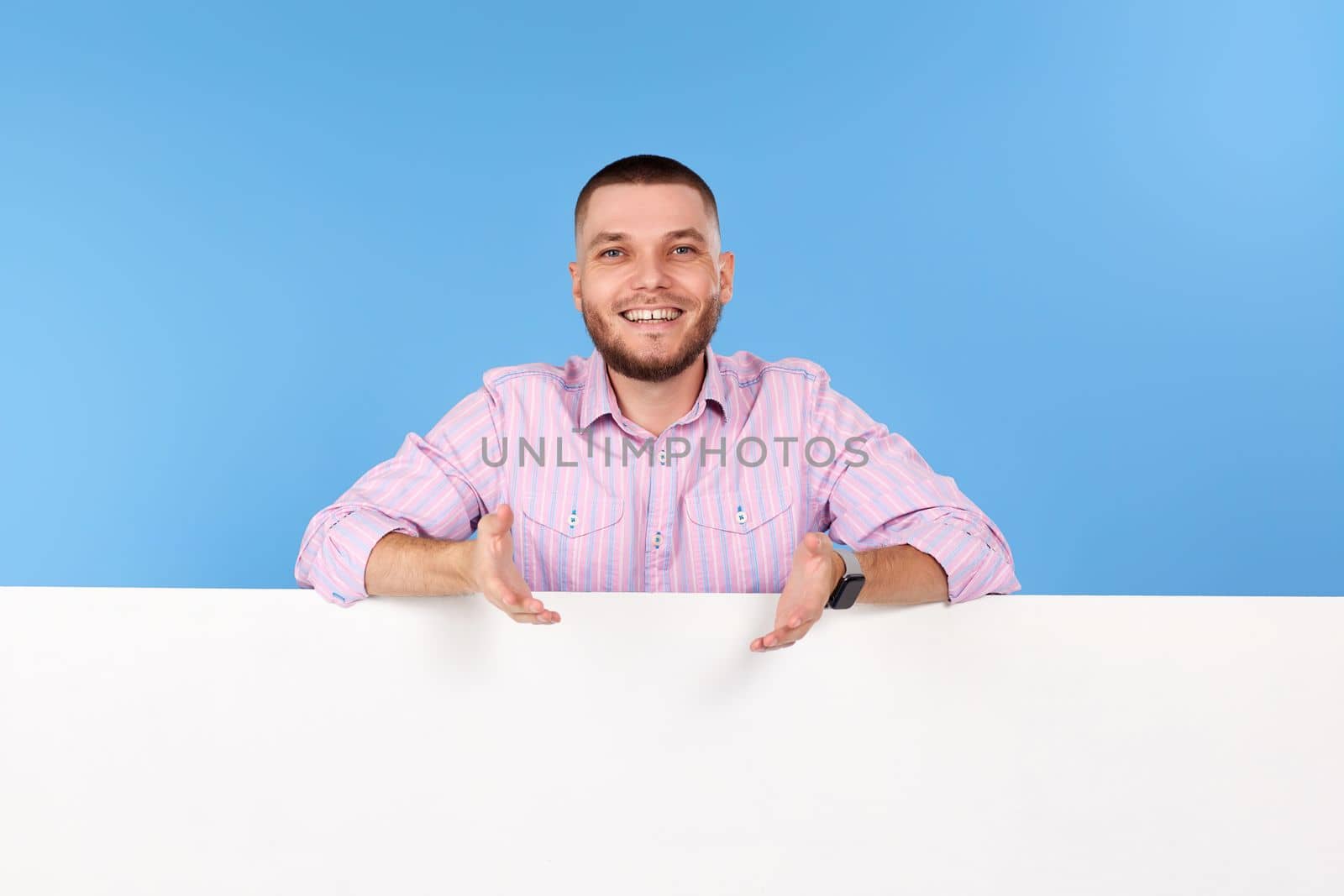 Portrait of cheerful man holding board with empty copy space isolated on blue background
