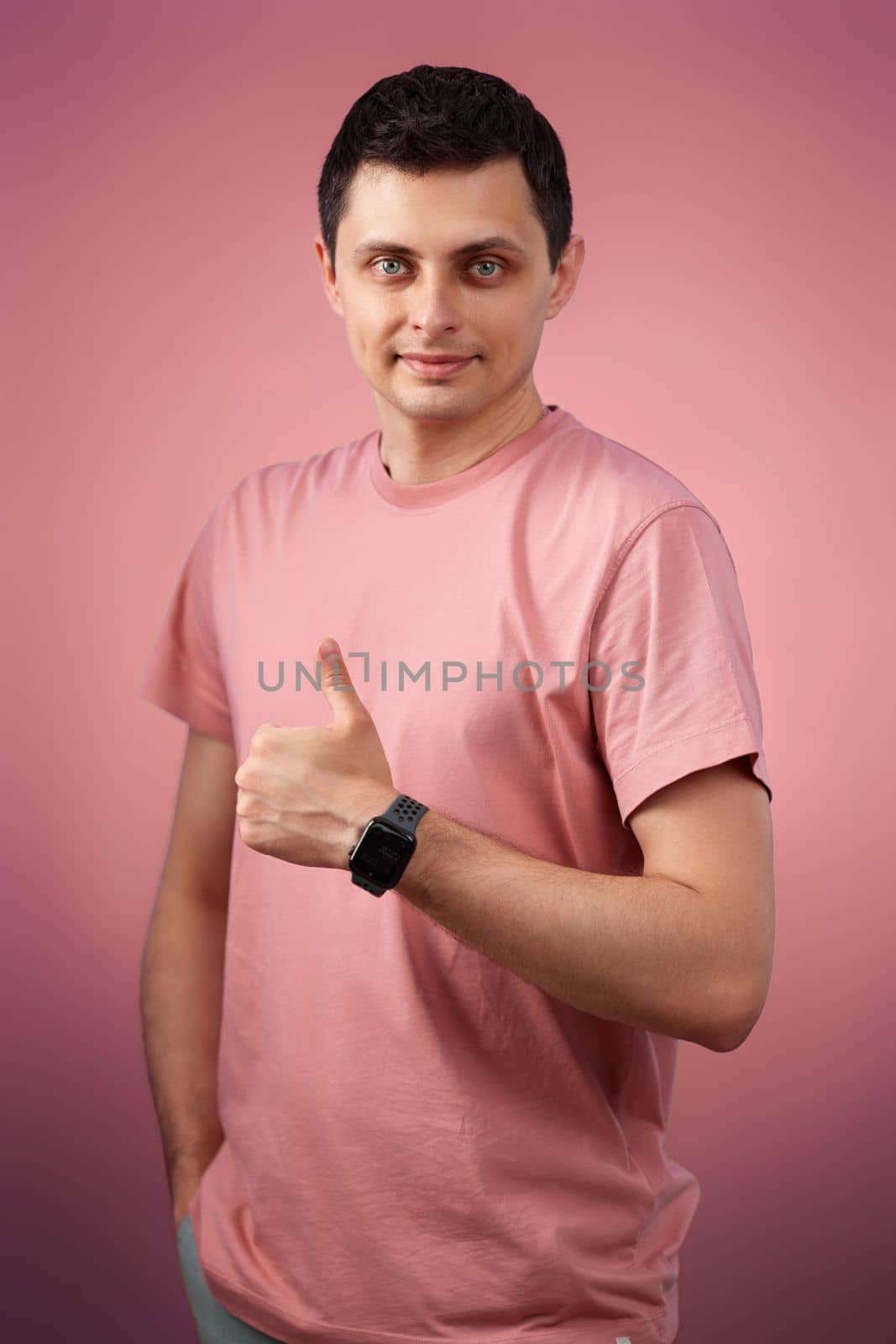 brunette man in t-shirt smiling and showing ok sign isolated on pink background