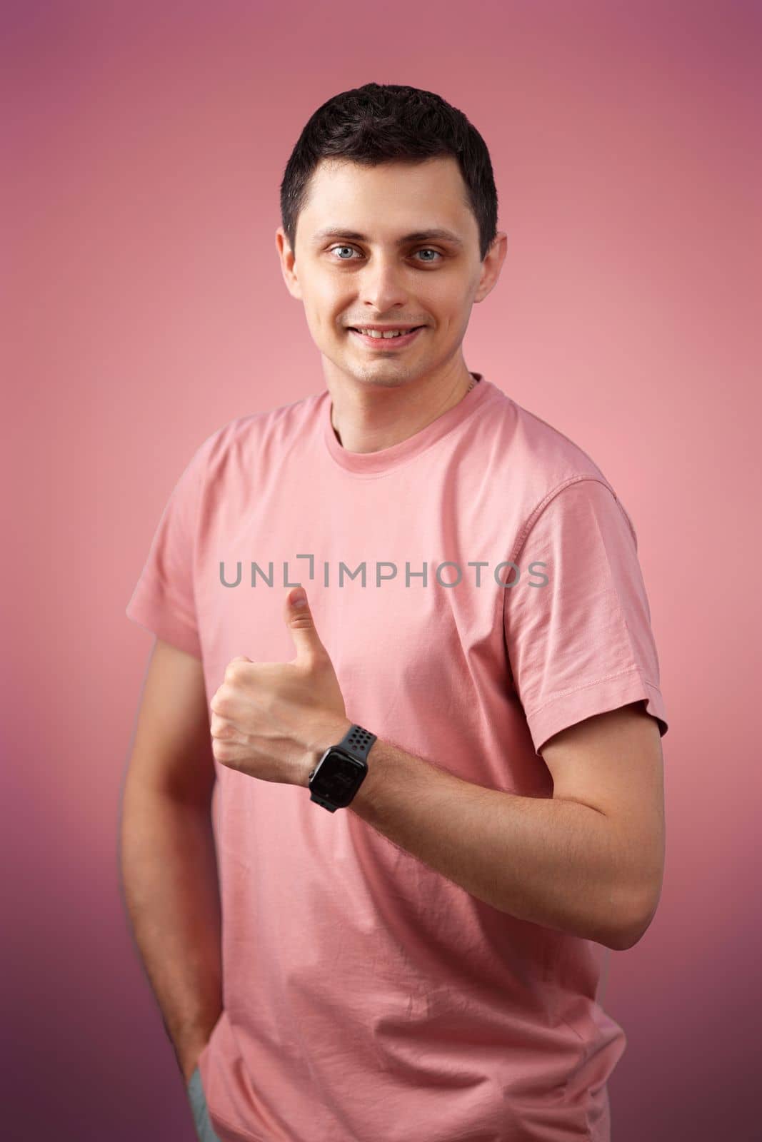 brunette man in t-shirt smiling and showing ok sign isolated on pink background