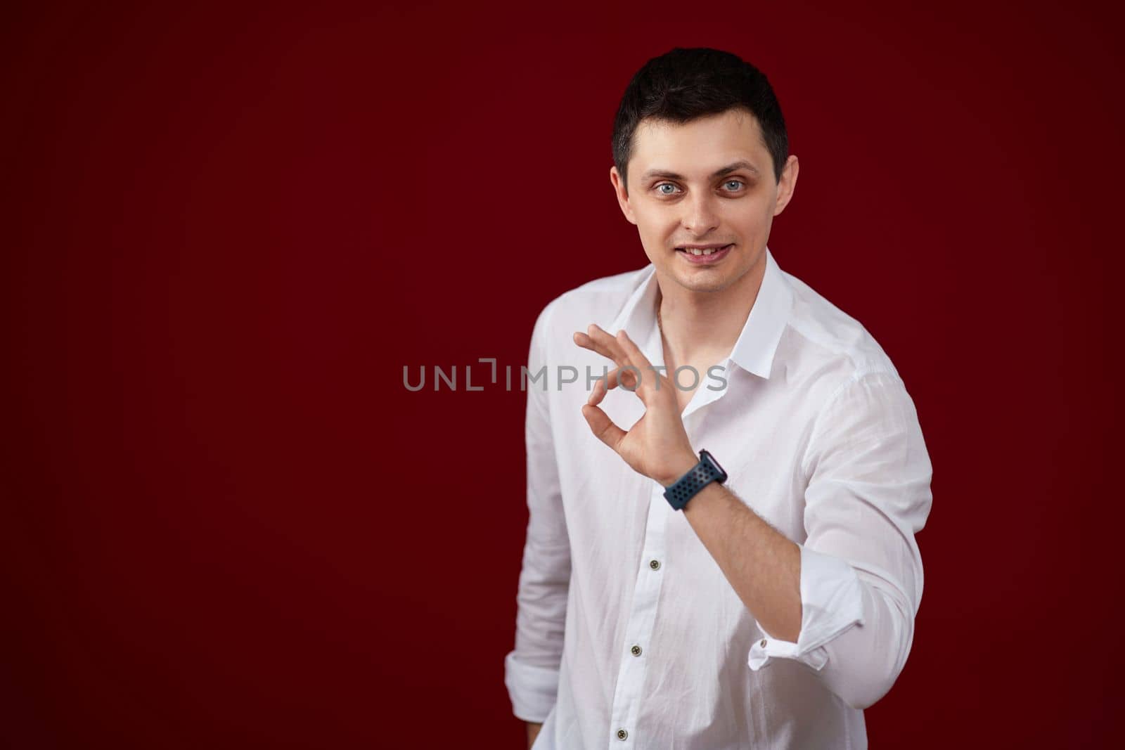 brunette man in t-shirt smiling and showing ok sign isolated on pink background