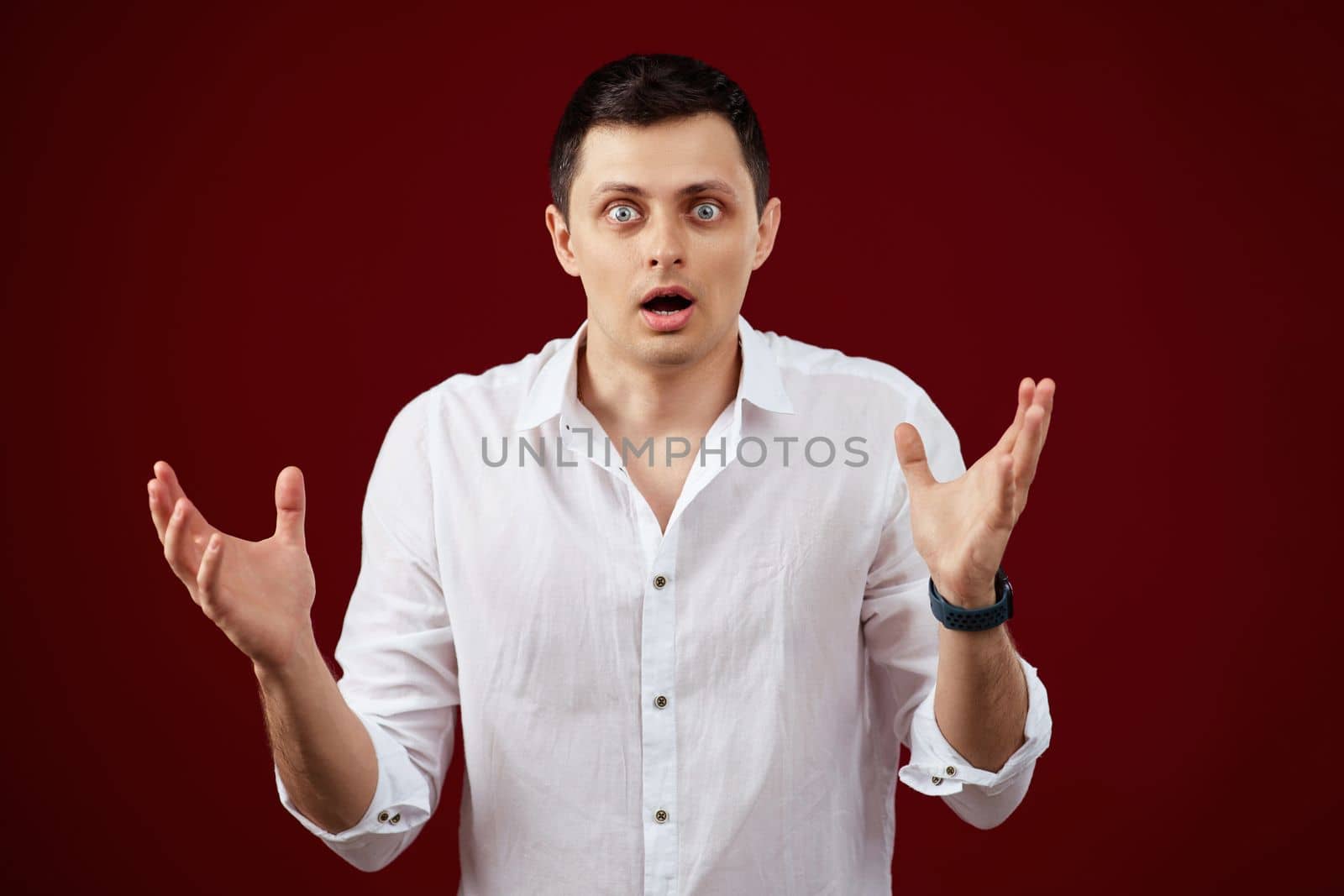 surprised shocked brunette man in white shirt isolated on red background