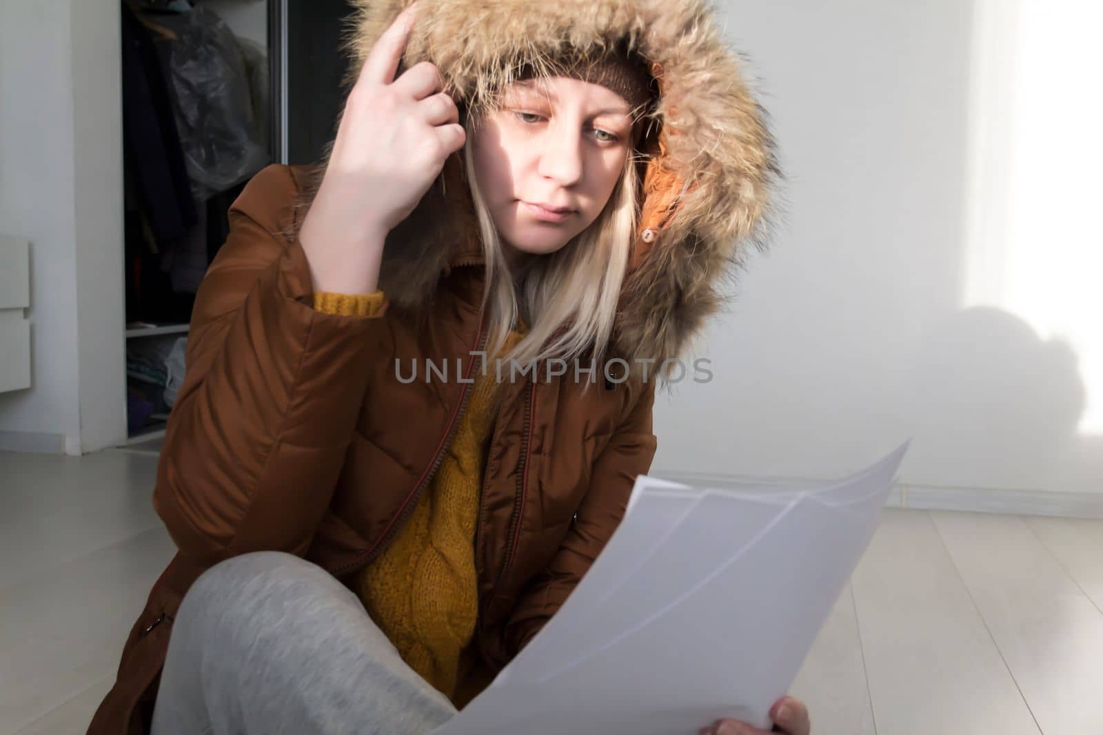 A man in a yellow sweater and jacket with documents in his hands. The concept of the economic crisis and large utility bills in homes. by Alla_Yurtayeva