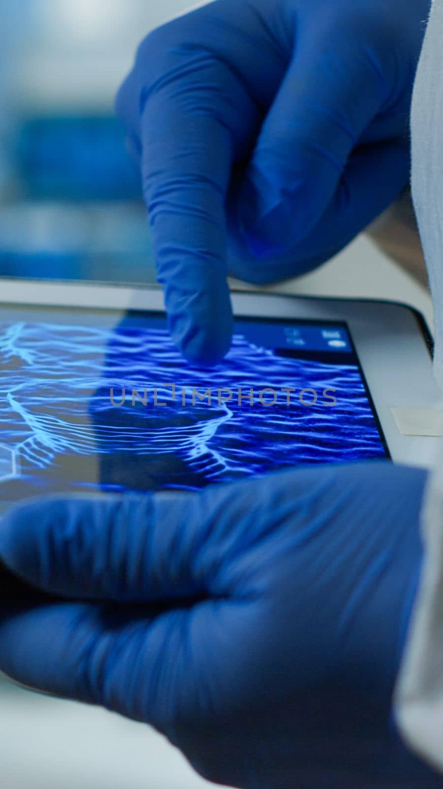 Close up of chemist doctor working on tablet with DNA scan image by DCStudio