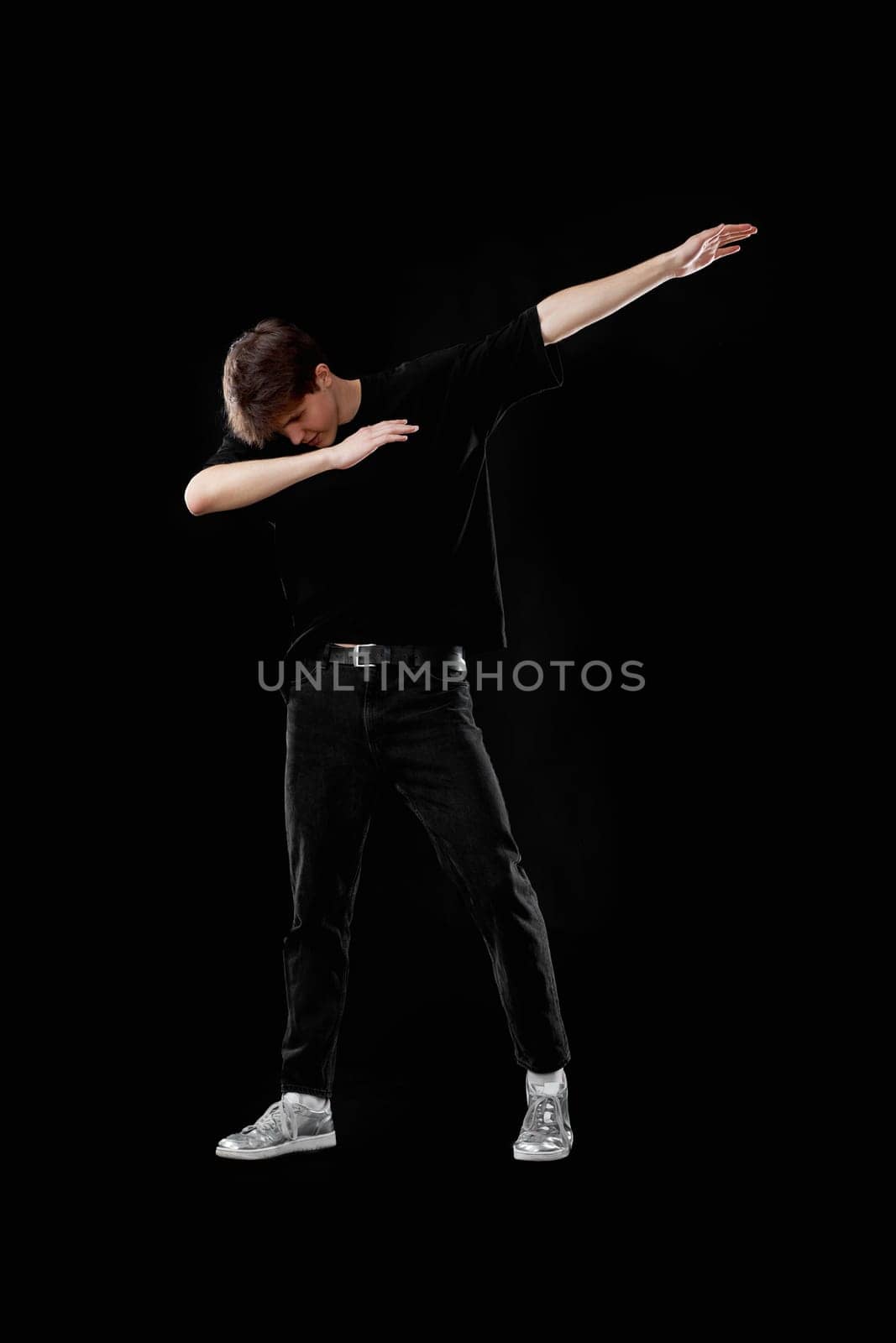 young man in black t-shirt dancing on black background. Full length