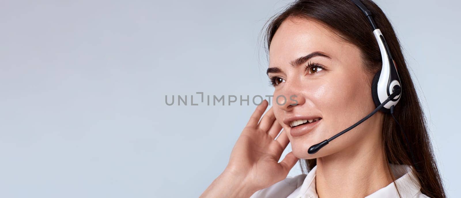 Portrait of beautiful woman in headset is consulting clients online. Call center, copy space