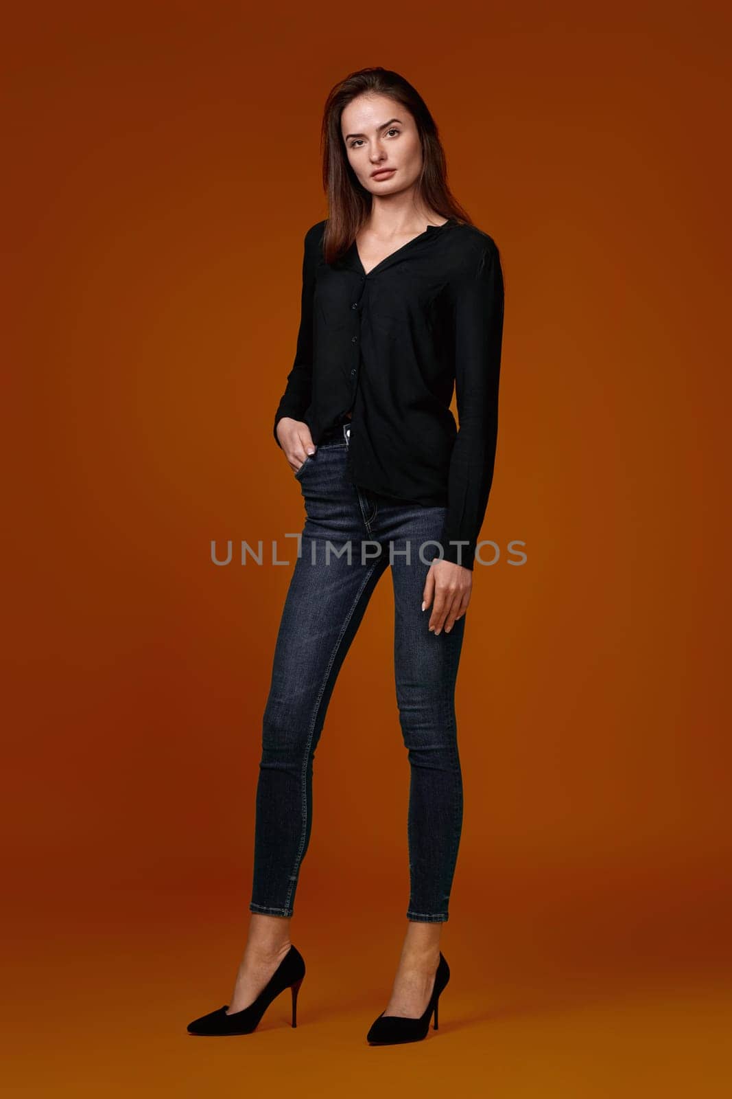 Full body woman in black shirt and jeans on color studio background.