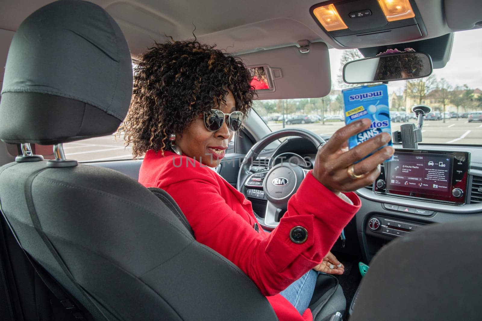 An African-American woman sits in a car and offers a Mentos candy to a passenger, Maasmechelen, Belgium February 17, 2023. High quality photo