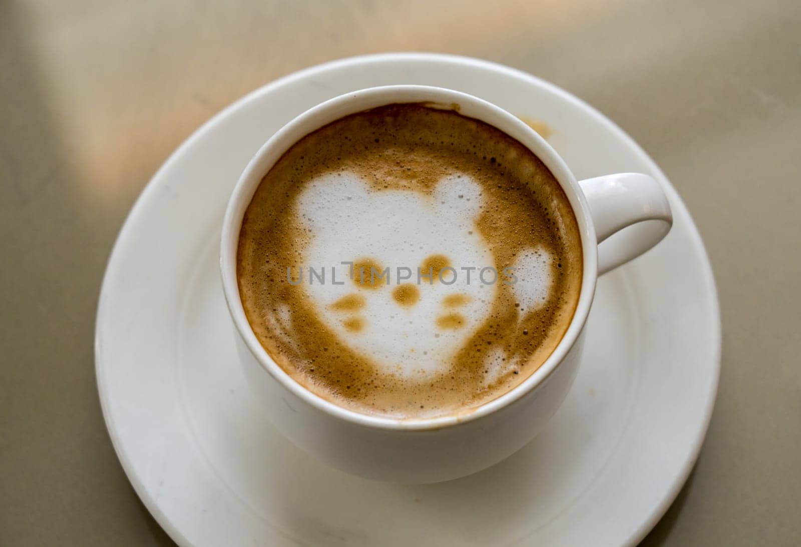 Shape of a cat or kittens face drawn in the milk foam or froth in top of cup of coffee