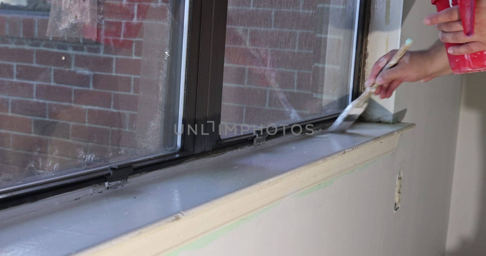Using paintbrush repairman paints window molding trim with during renovations to an apartment