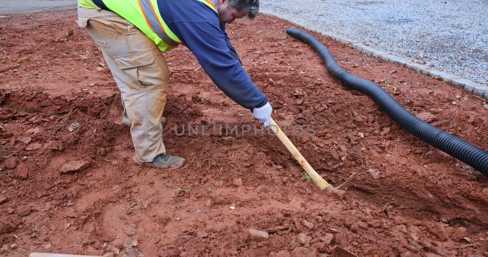 During major rainfall worker digs trench so as to lay drainage pipe for collect rainwater