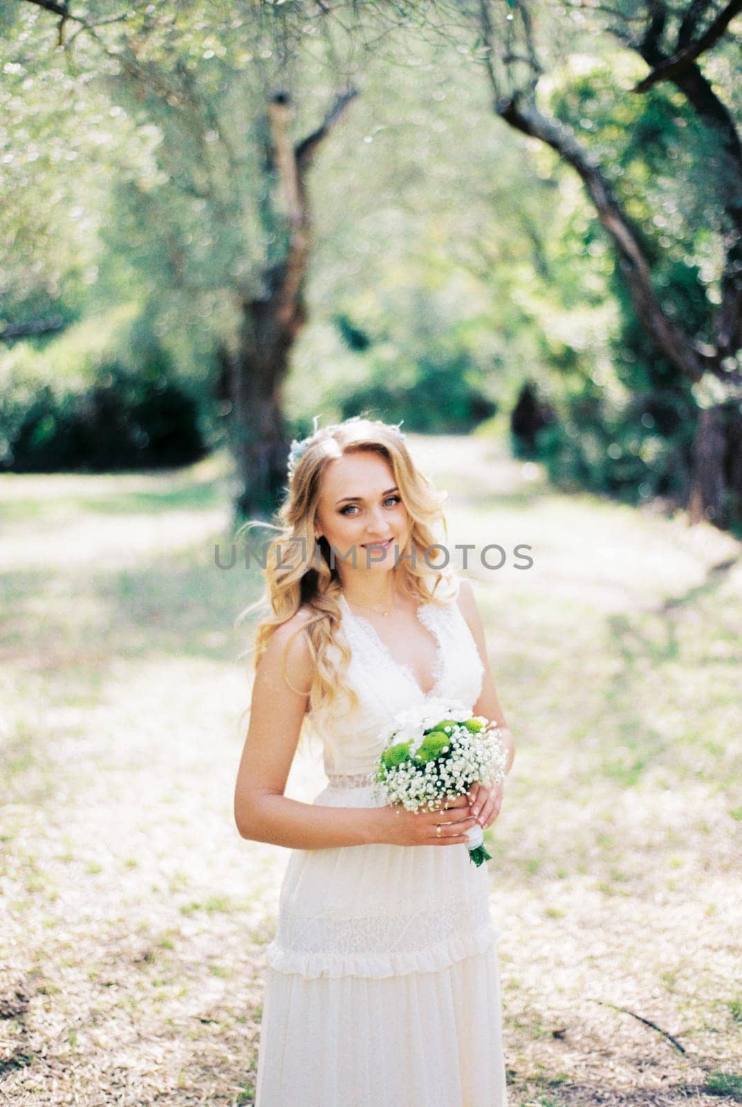 Bride with a bouquet of flowers stands on a sunny meadow in the park. High quality photo
