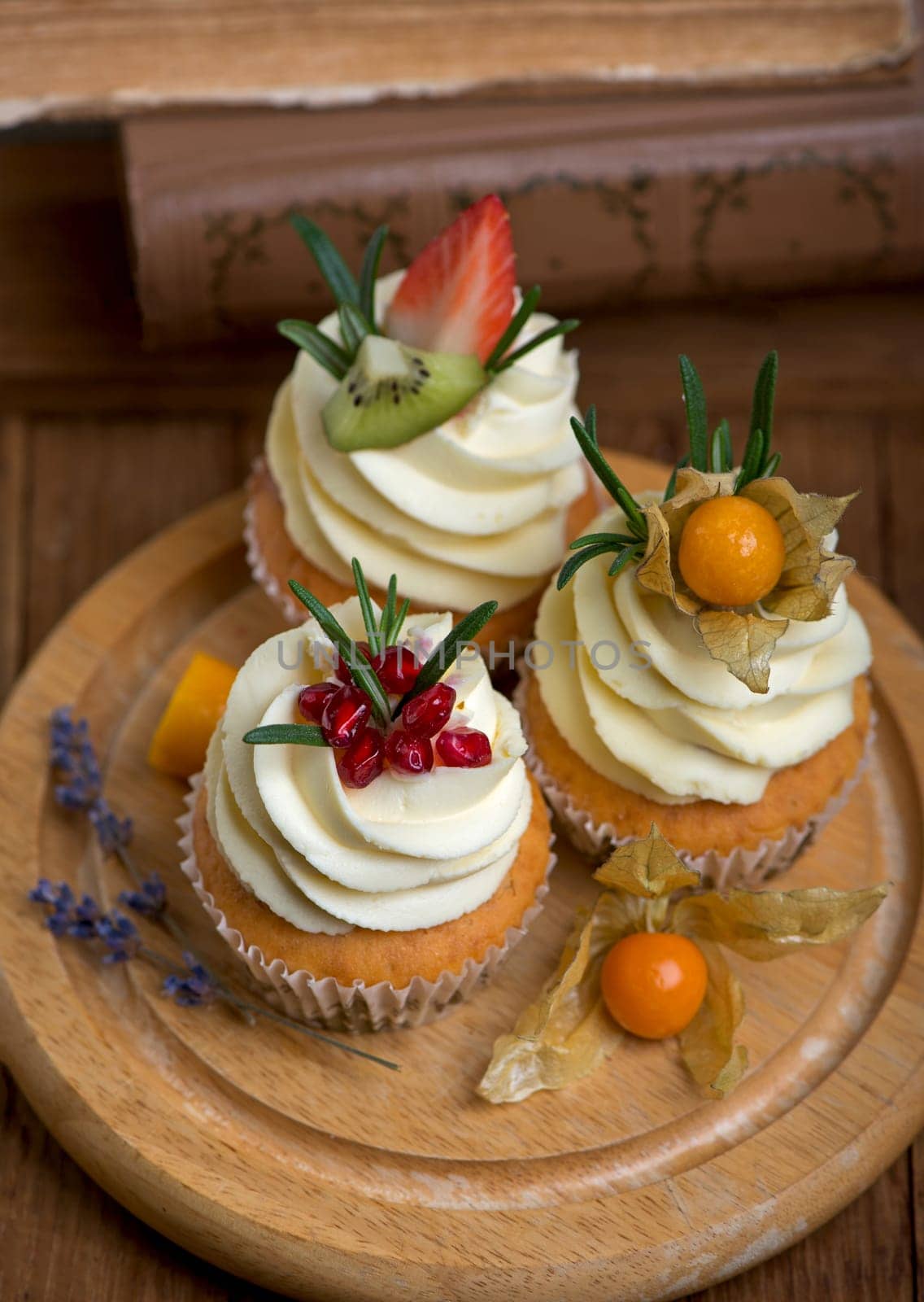 cupcakes with cream decorated with fresh fruits on a wooden