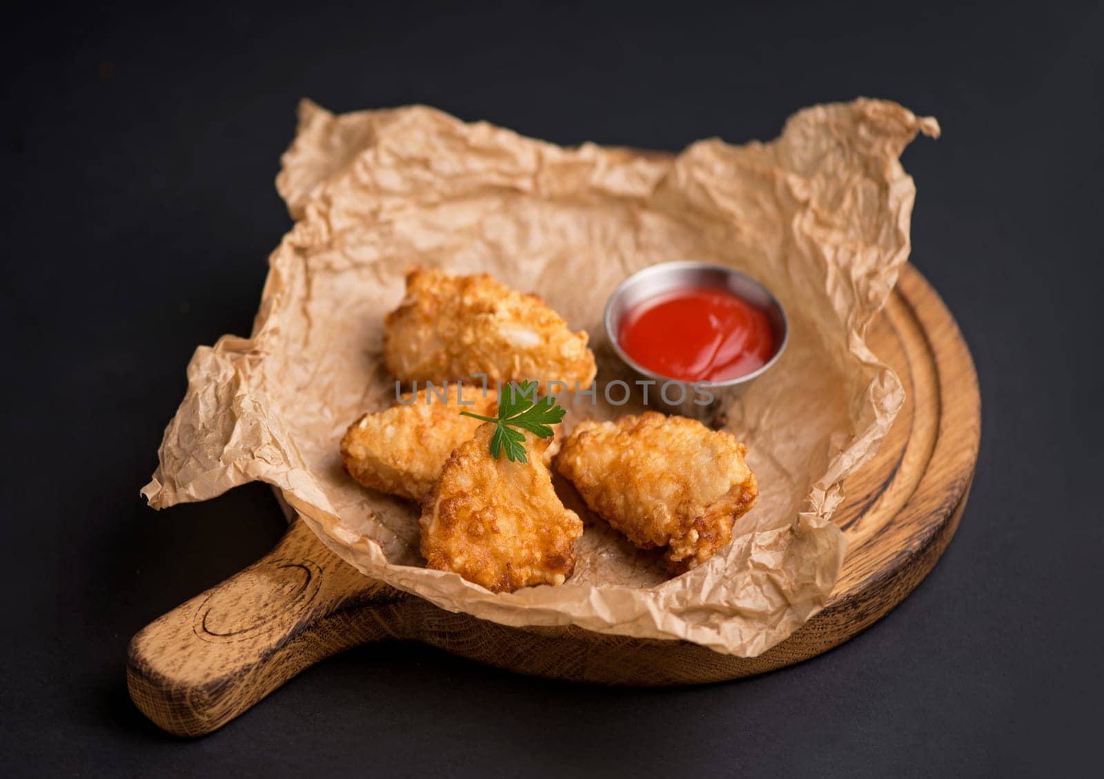 beer snacks - chicken fillet fried in batter with sauce on a wooden board on a black background by aprilphoto